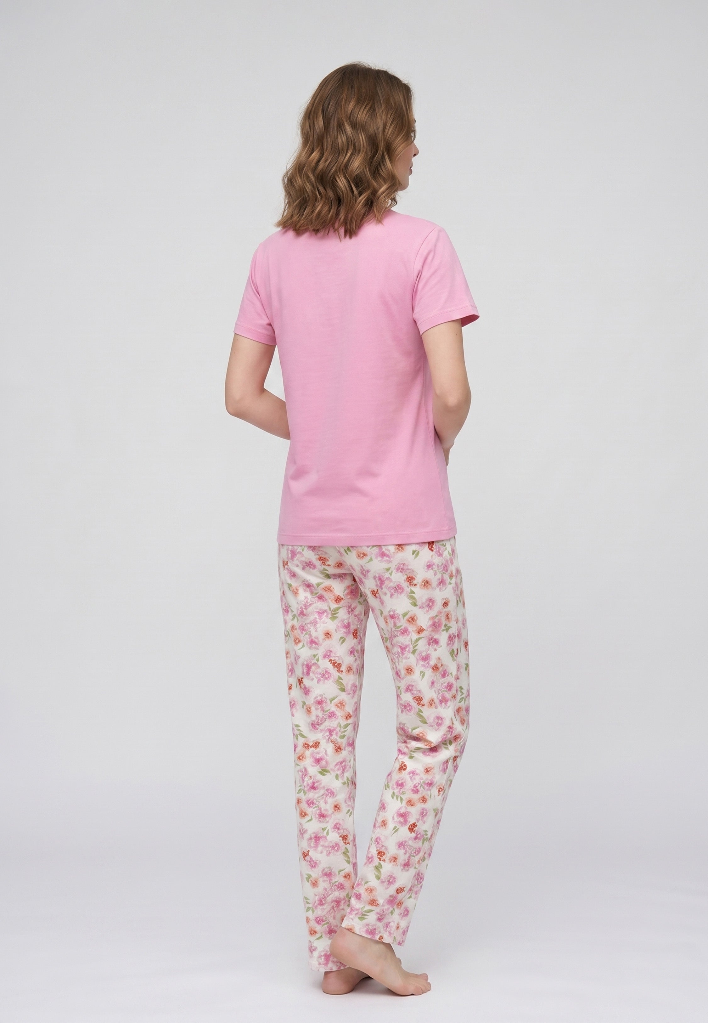 Femme portant un pyjama deux pièces t-shirt rose col V liseré fleuri et pantalon long imprimé fleuri multicolore Rosabella Floralys