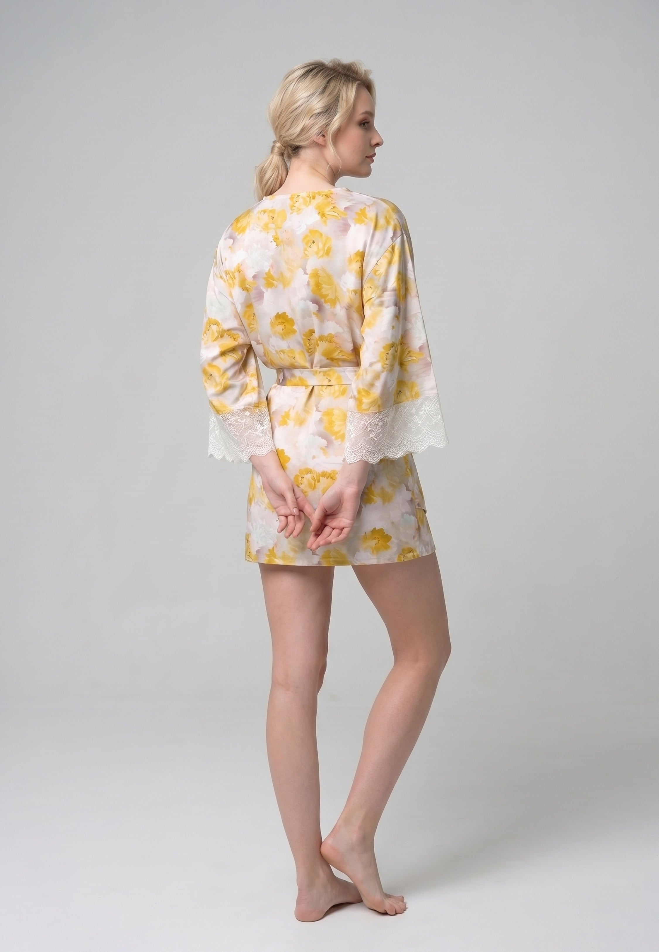 Femme portant un peignoir court croisé manches longues évasées dentelle imprimé fleuri jaune et rose avec ceinture Rosabella Summer Time
