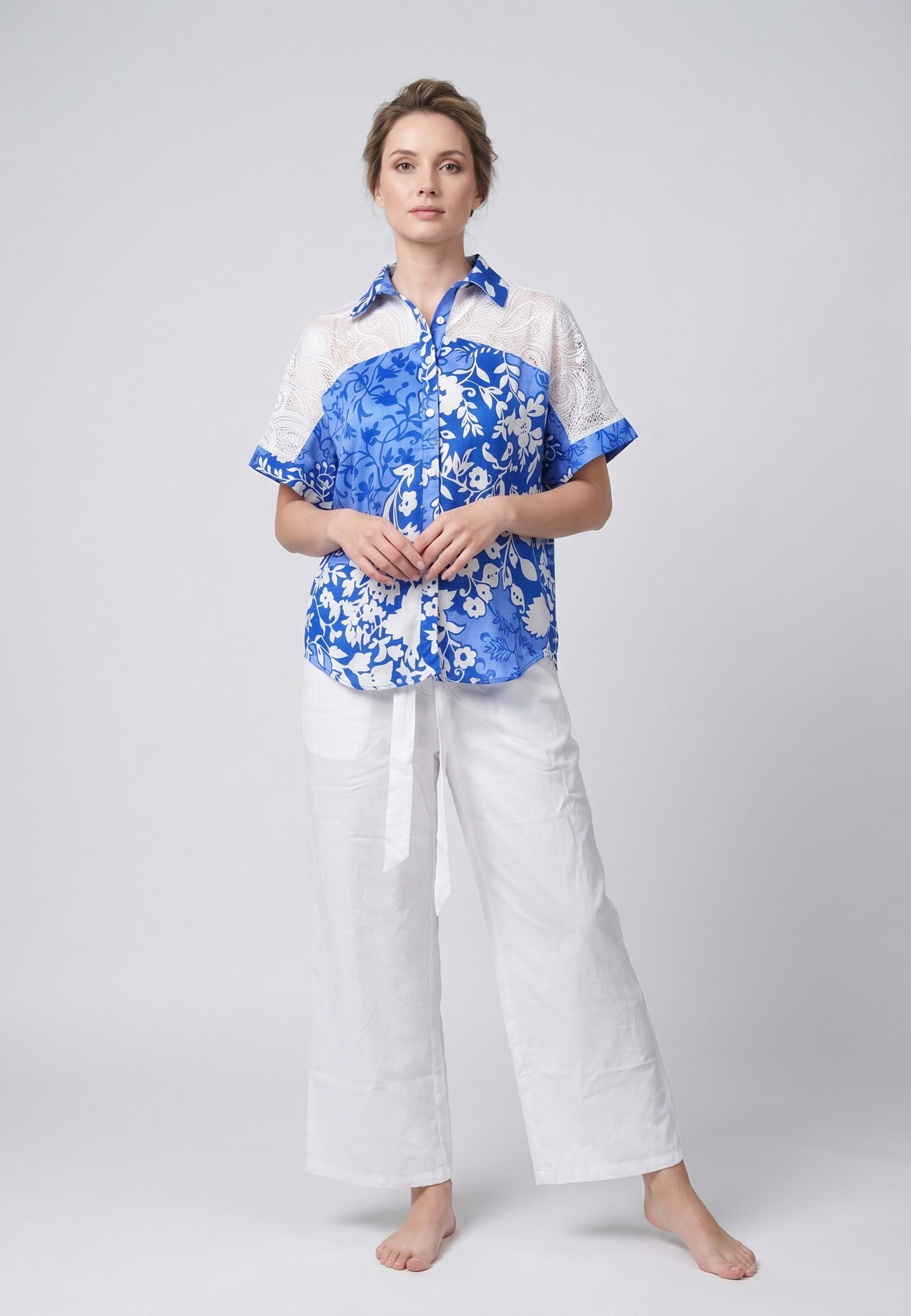 Femme portant un pyjama deux pièces chemise boutonnée dentelle crochet imprimé fleuri bleu et blanc et pantalon large uni blanc Rosabella Jasmine Nights