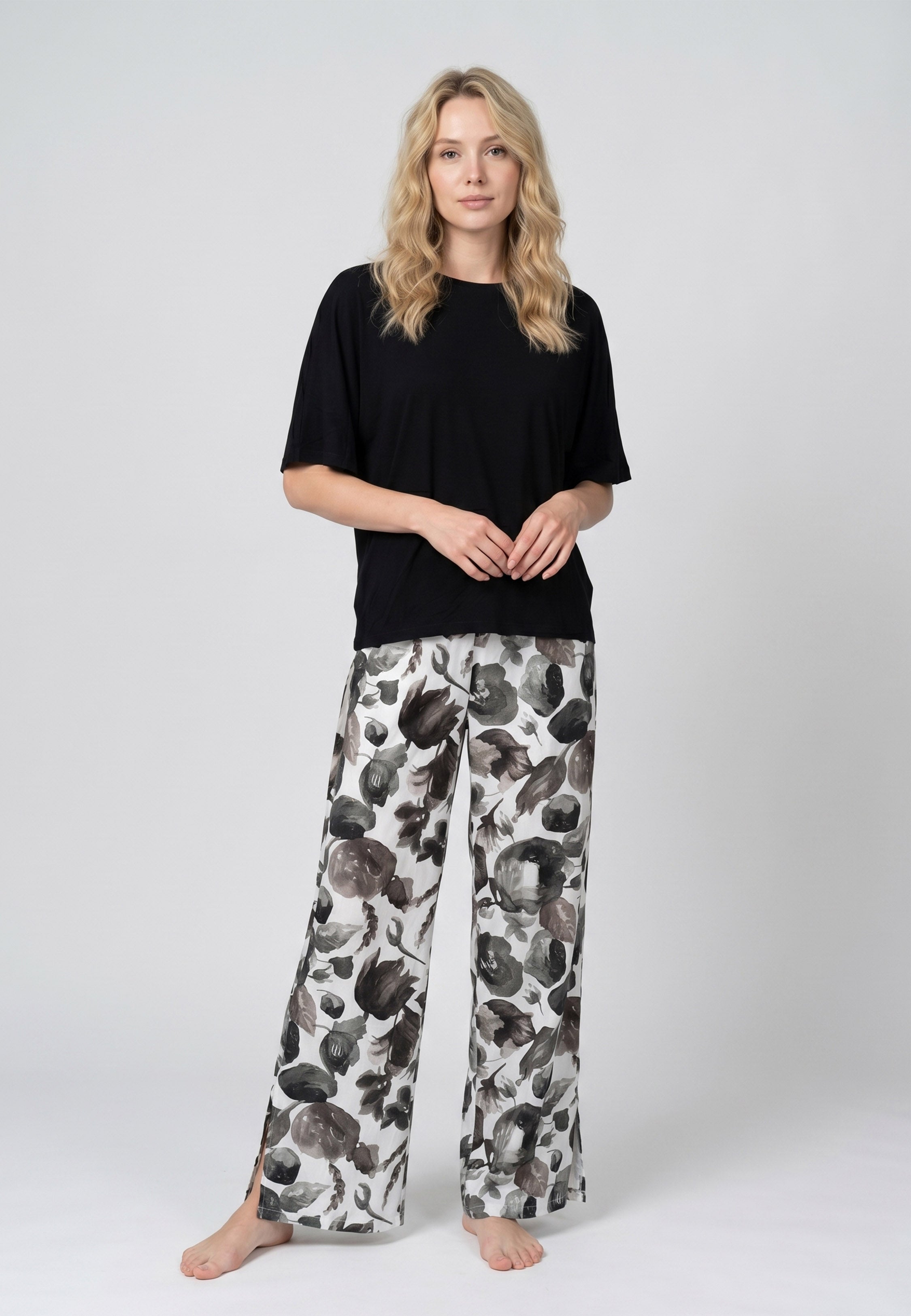 Femme portant un pyjama deux pièces t-shirt oversize uni noir et pantalon large imprimé fleuri noir et blanc Rosabella Cozy Comforts