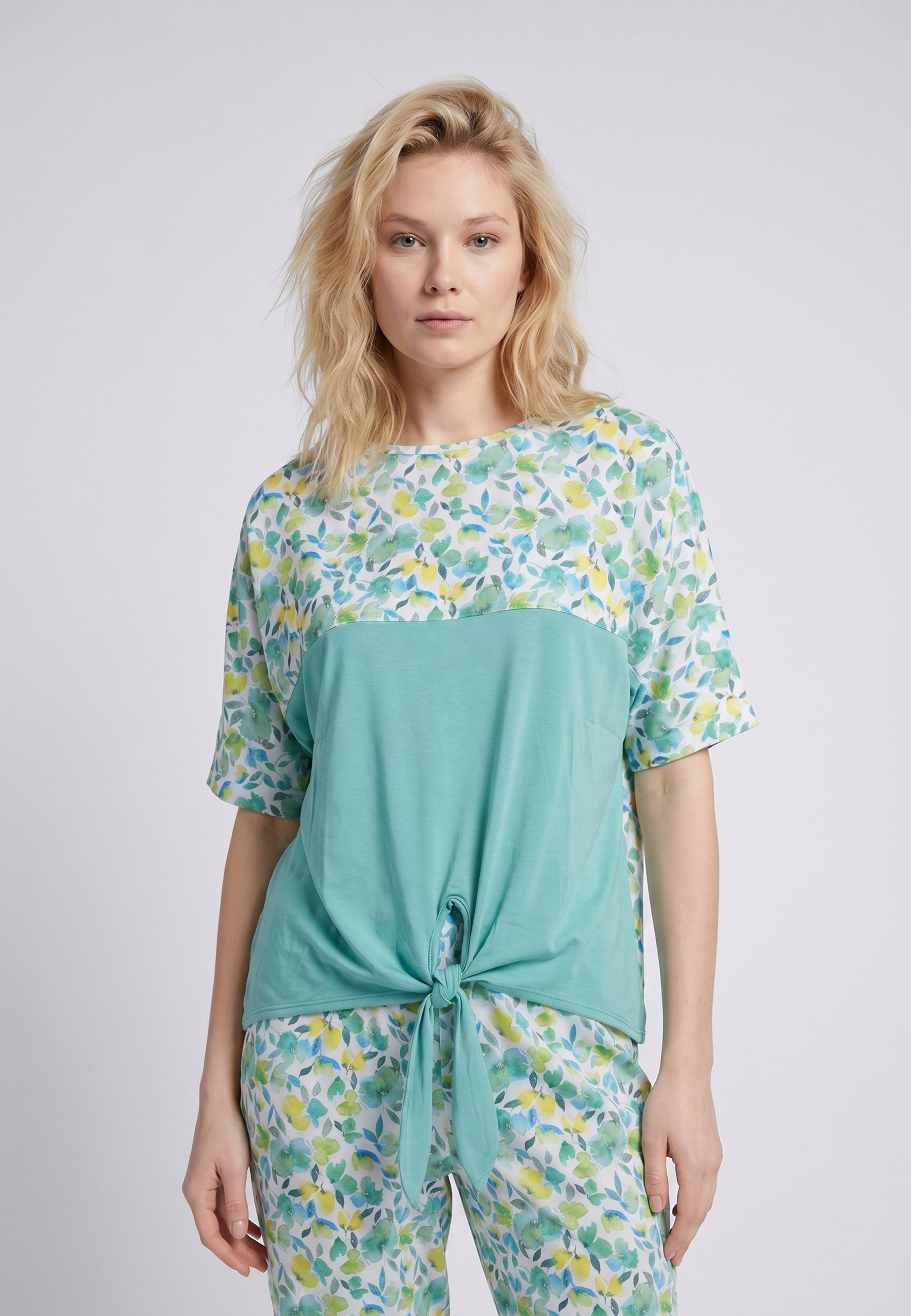 Femme portant un pyjama deux pièces top col rond bicolore nœud frontal empiècement fleuri et pantalon long imprimé fleuri vert et jaune Rosabella Soft Embrace