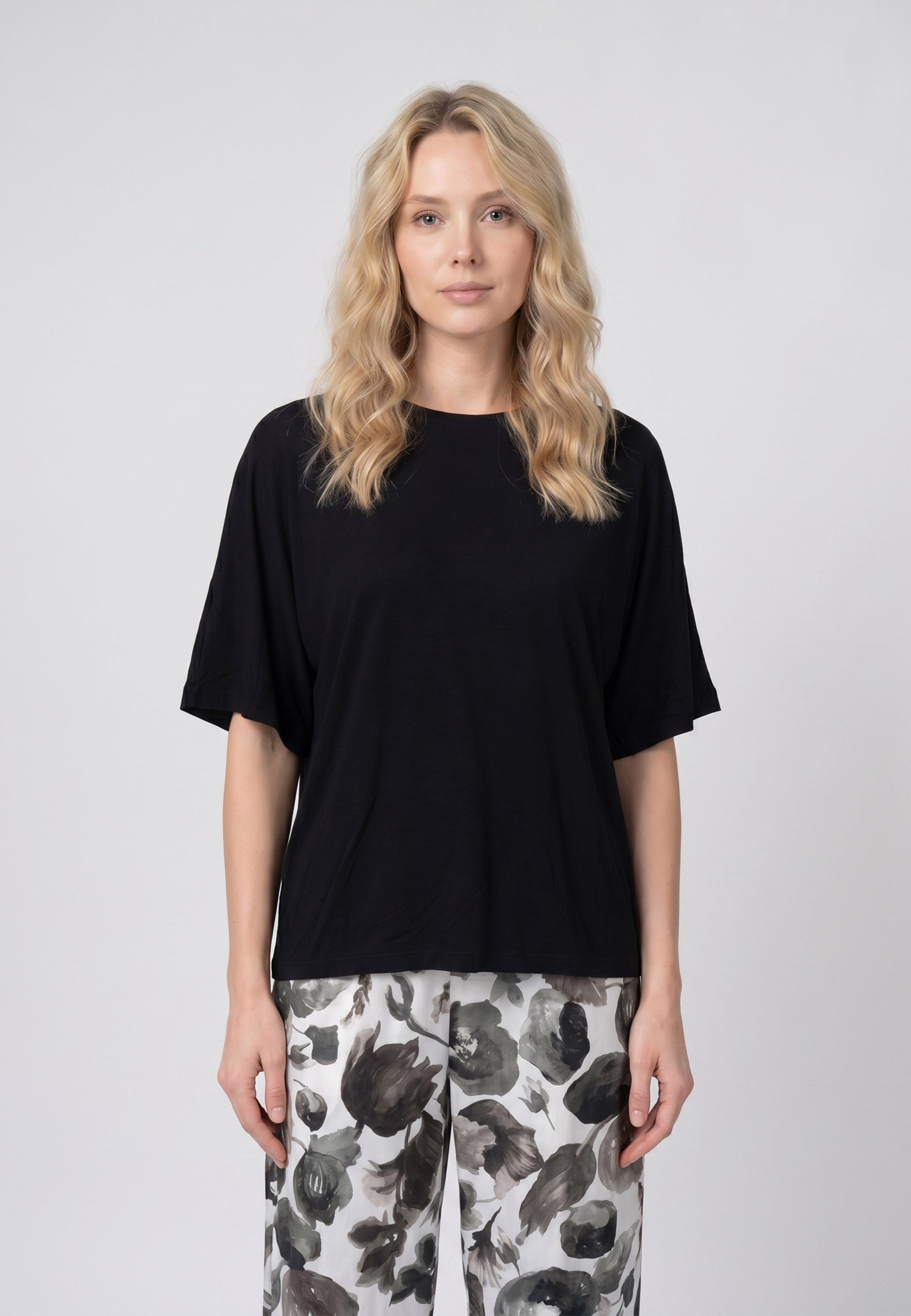 Femme portant un pyjama deux pièces t-shirt oversize uni noir et pantalon large imprimé fleuri noir et blanc Rosabella Cozy Comforts
