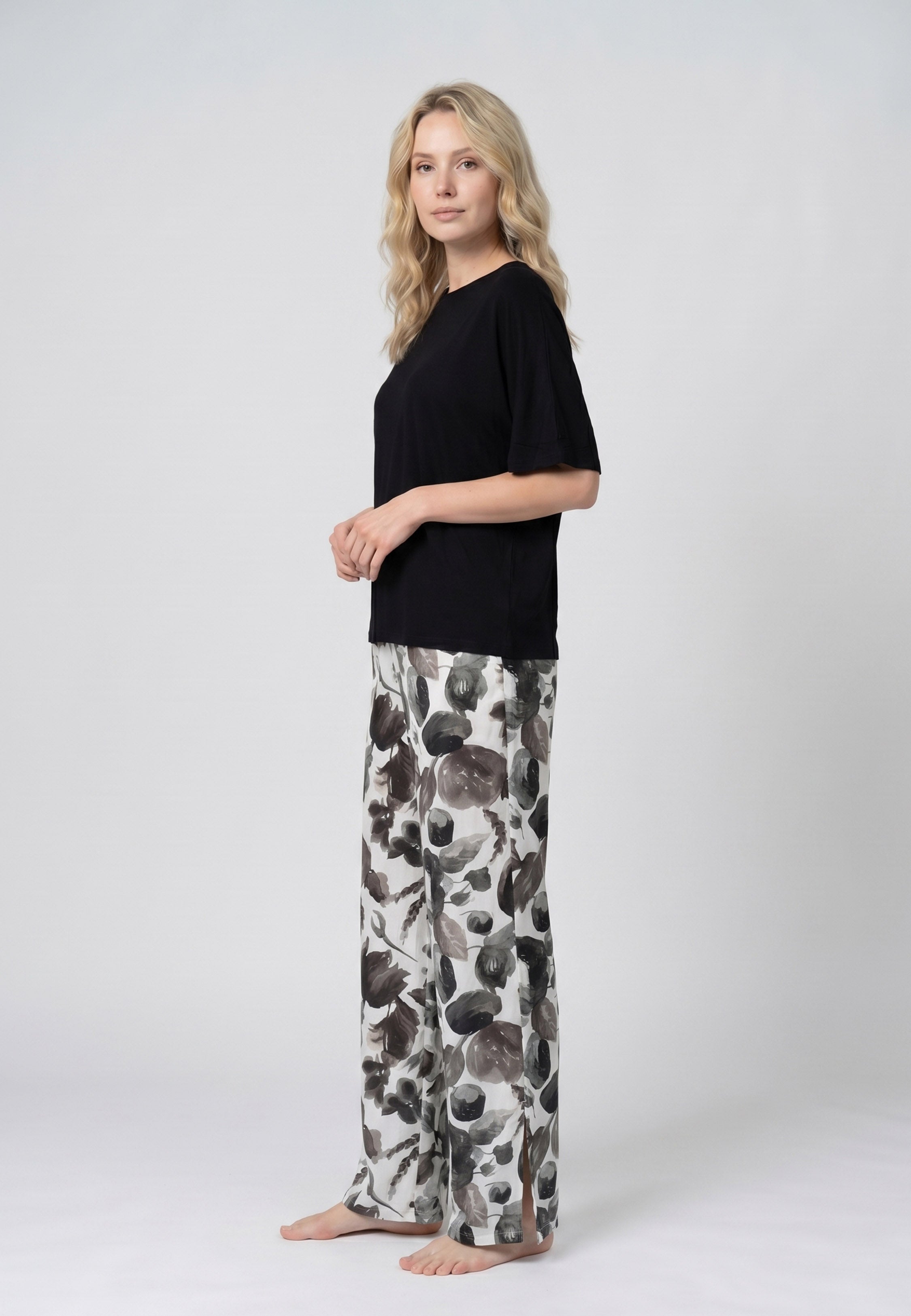 Femme portant un pyjama deux pièces t-shirt oversize uni noir et pantalon large imprimé fleuri noir et blanc Rosabella Cozy Comforts