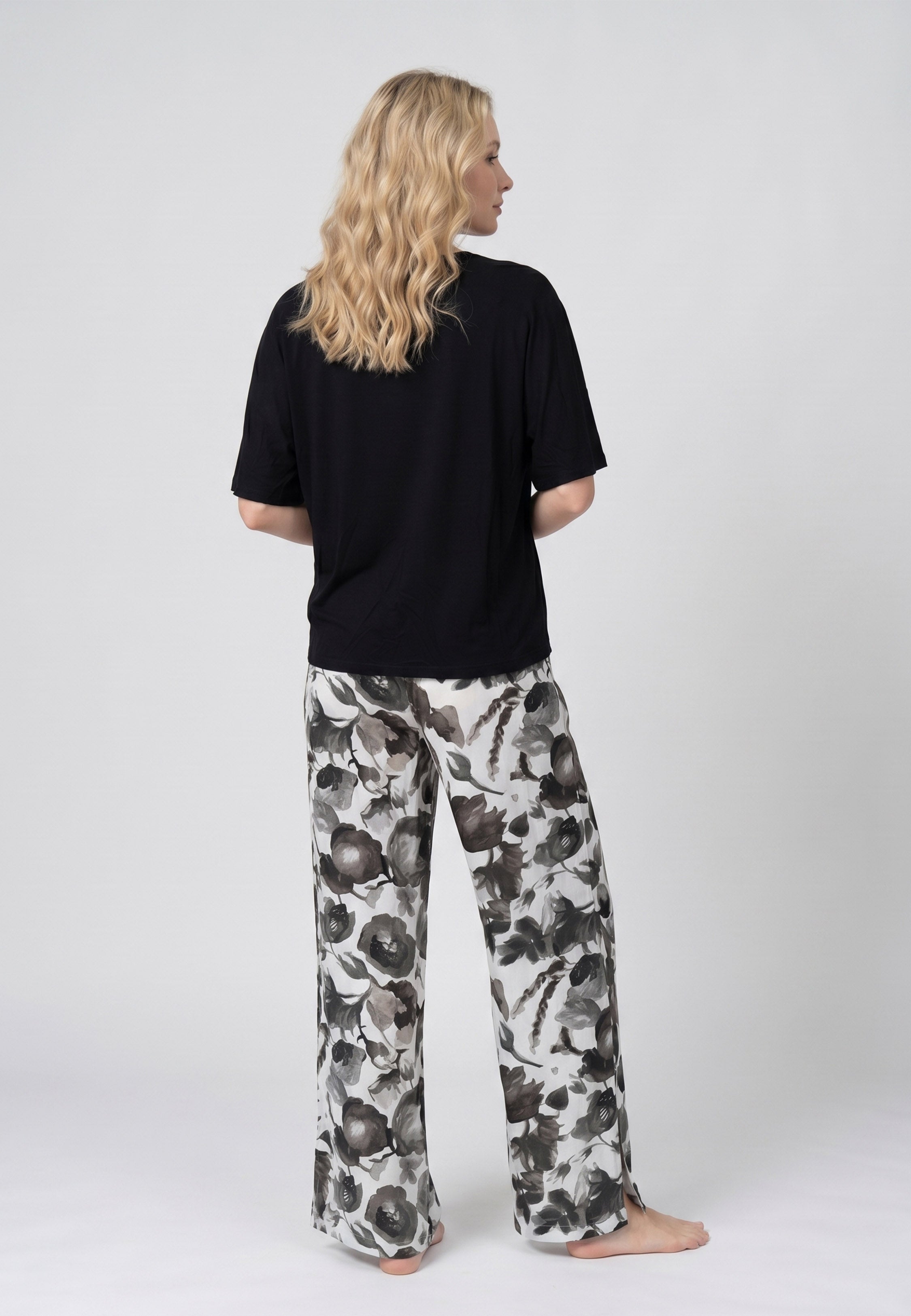 Femme portant un pyjama deux pièces t-shirt oversize uni noir et pantalon large imprimé fleuri noir et blanc Rosabella Cozy Comforts