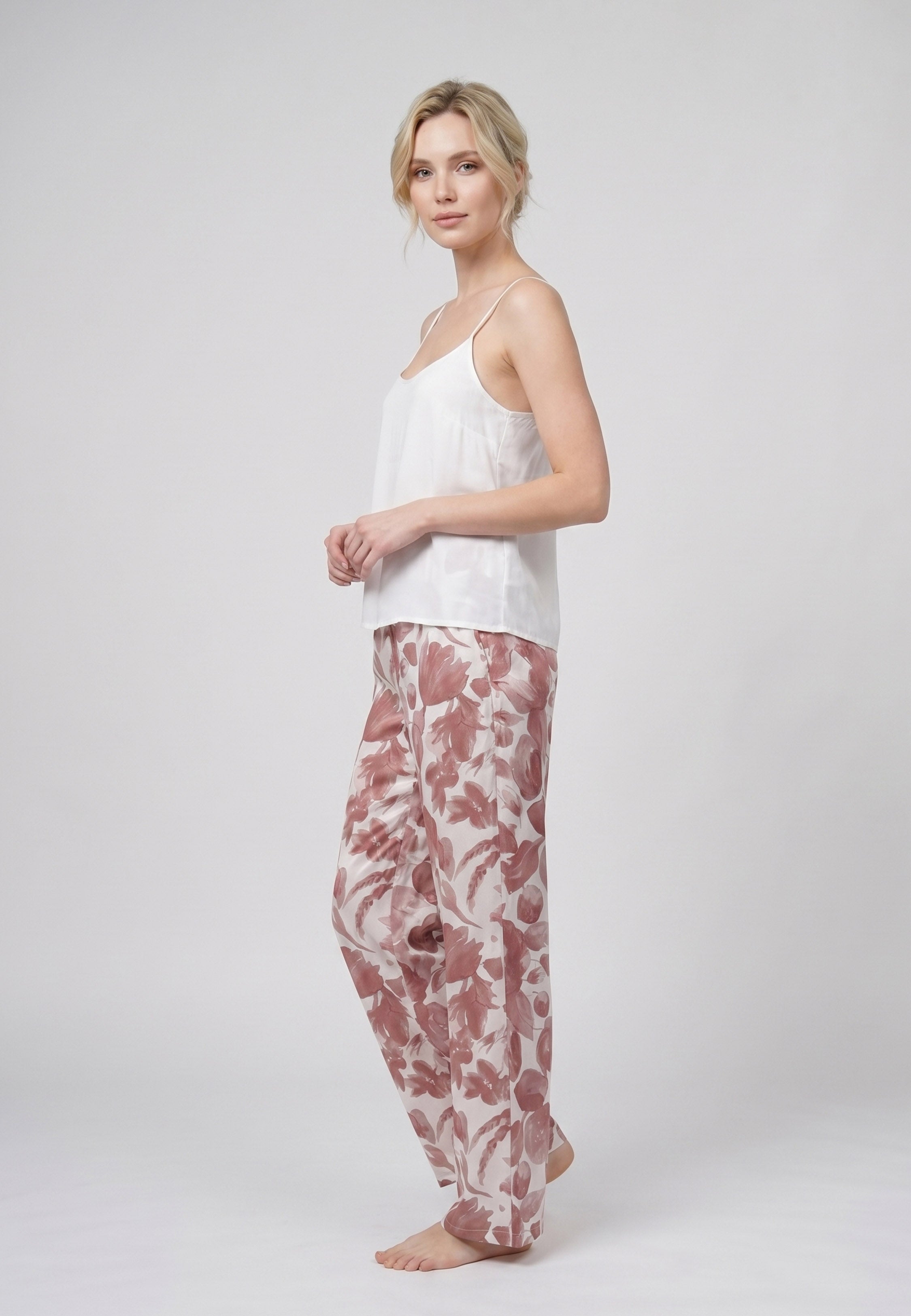 Femme portant un pyjama deux pièces débardeur bretelles fines uni ivoire et pantalon large imprimé fleuri aquarelle bordeaux et rose Rosabella Cozy Comforts