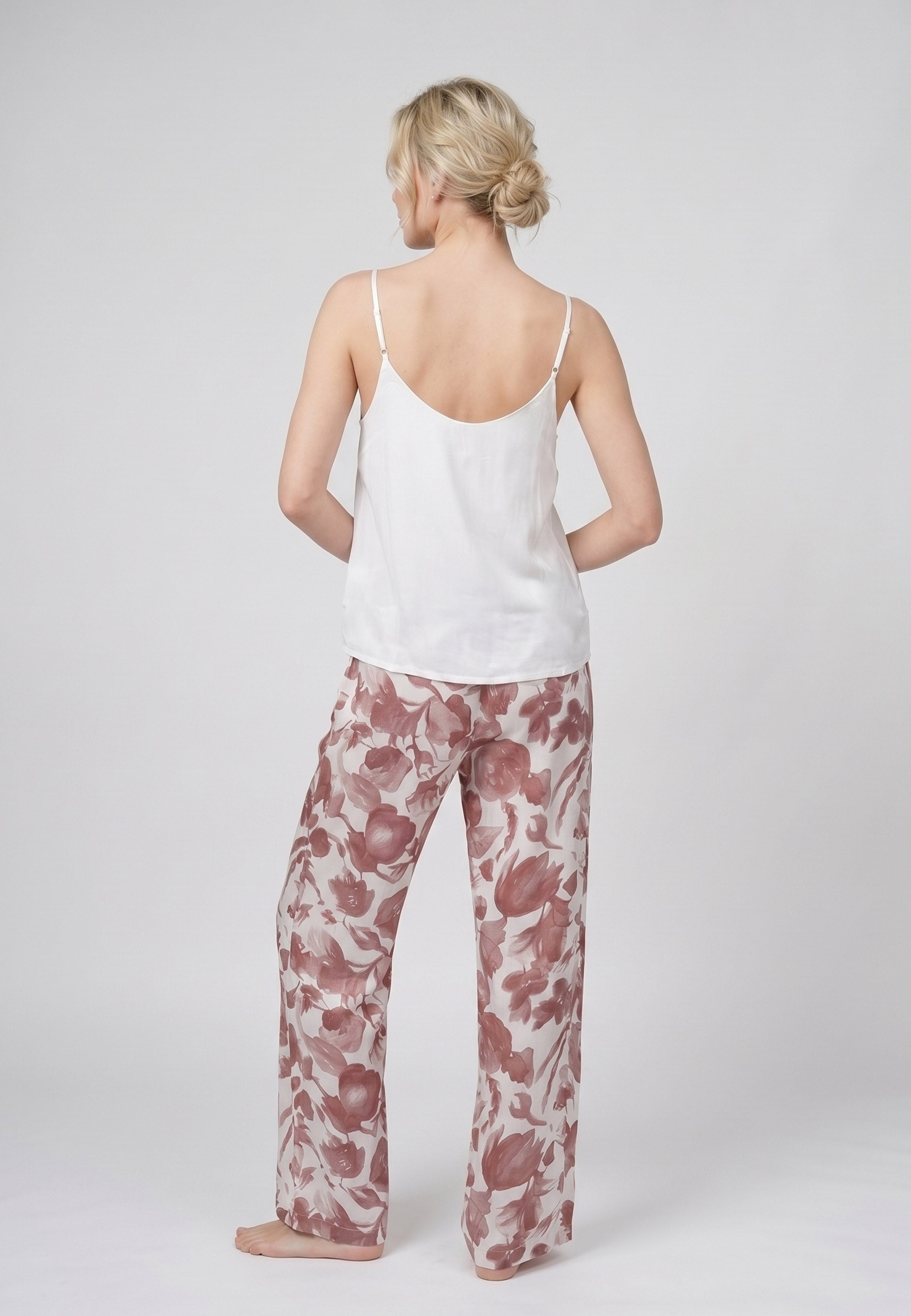 Femme portant un pyjama deux pièces débardeur bretelles fines uni ivoire et pantalon large imprimé fleuri aquarelle bordeaux et rose Rosabella Cozy Comforts