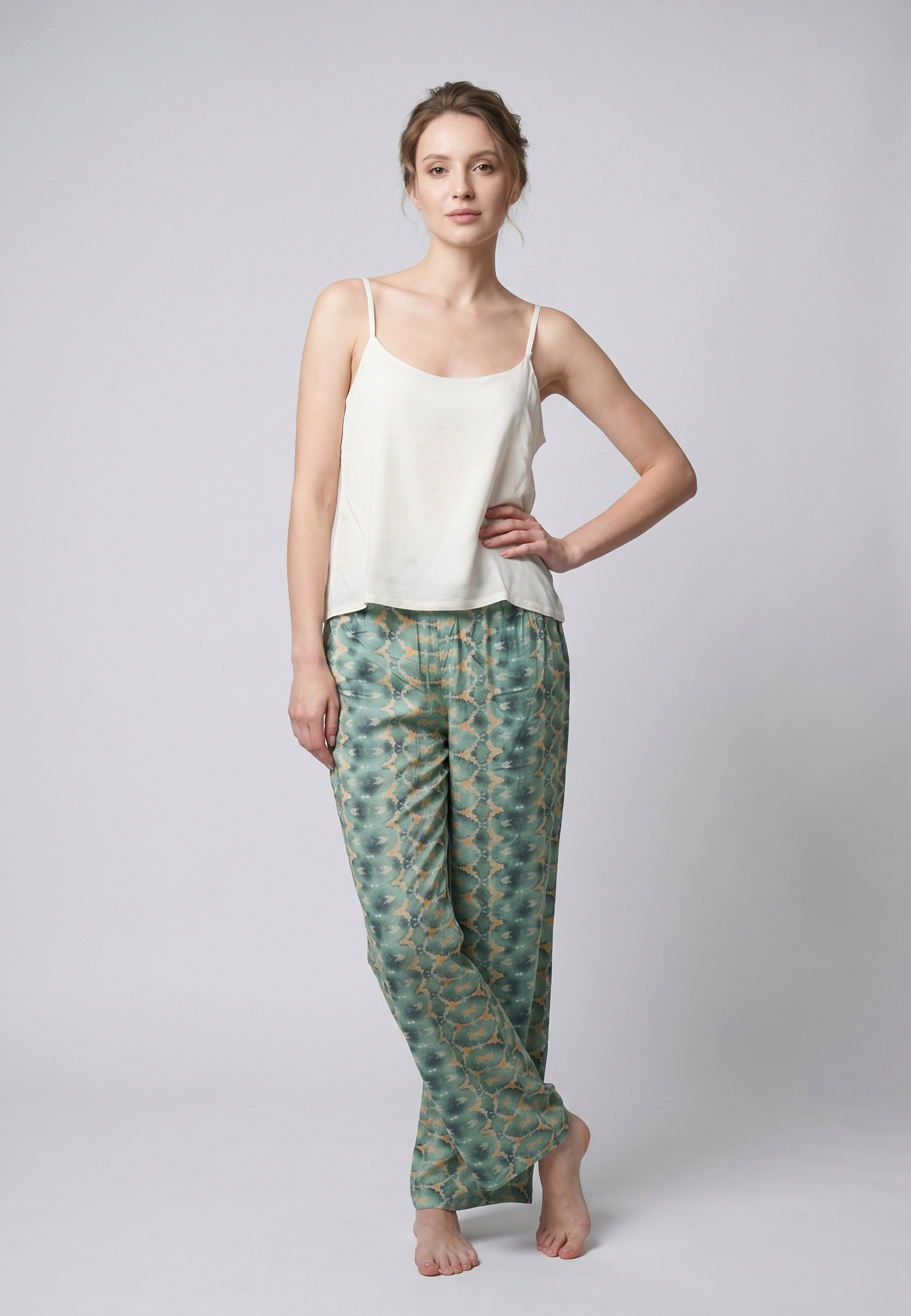 Femme portant un pyjama deux pièces débardeur bretelles fines uni ivoire et pantalon large imprimé fleuri aquarelle vert et blanc Rosabella Cozy Comforts