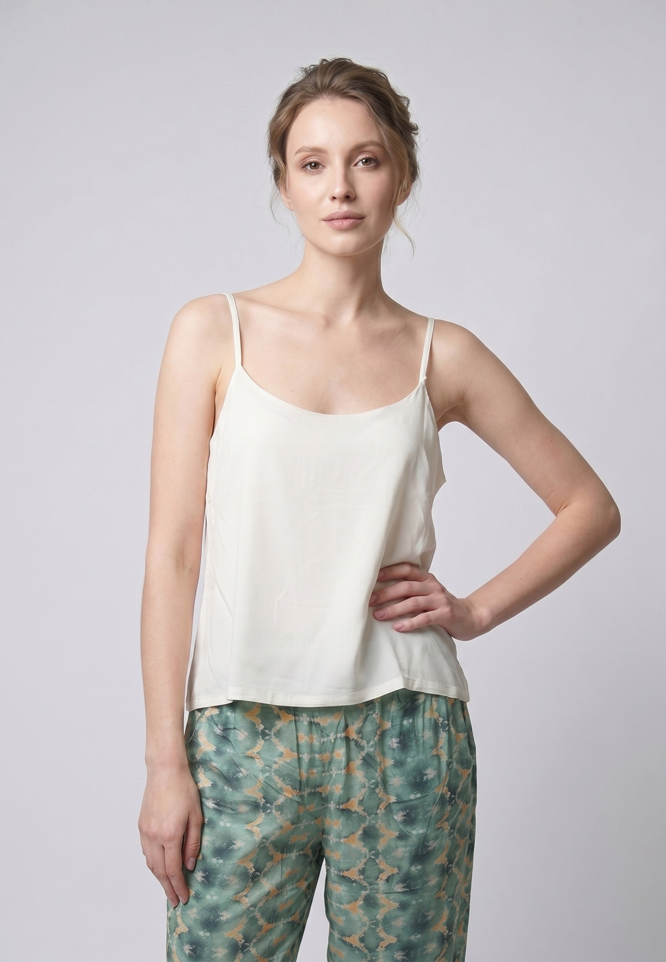 Femme portant un pyjama deux pièces débardeur bretelles fines uni ivoire et pantalon large imprimé fleuri aquarelle vert et blanc Rosabella Cozy Comforts