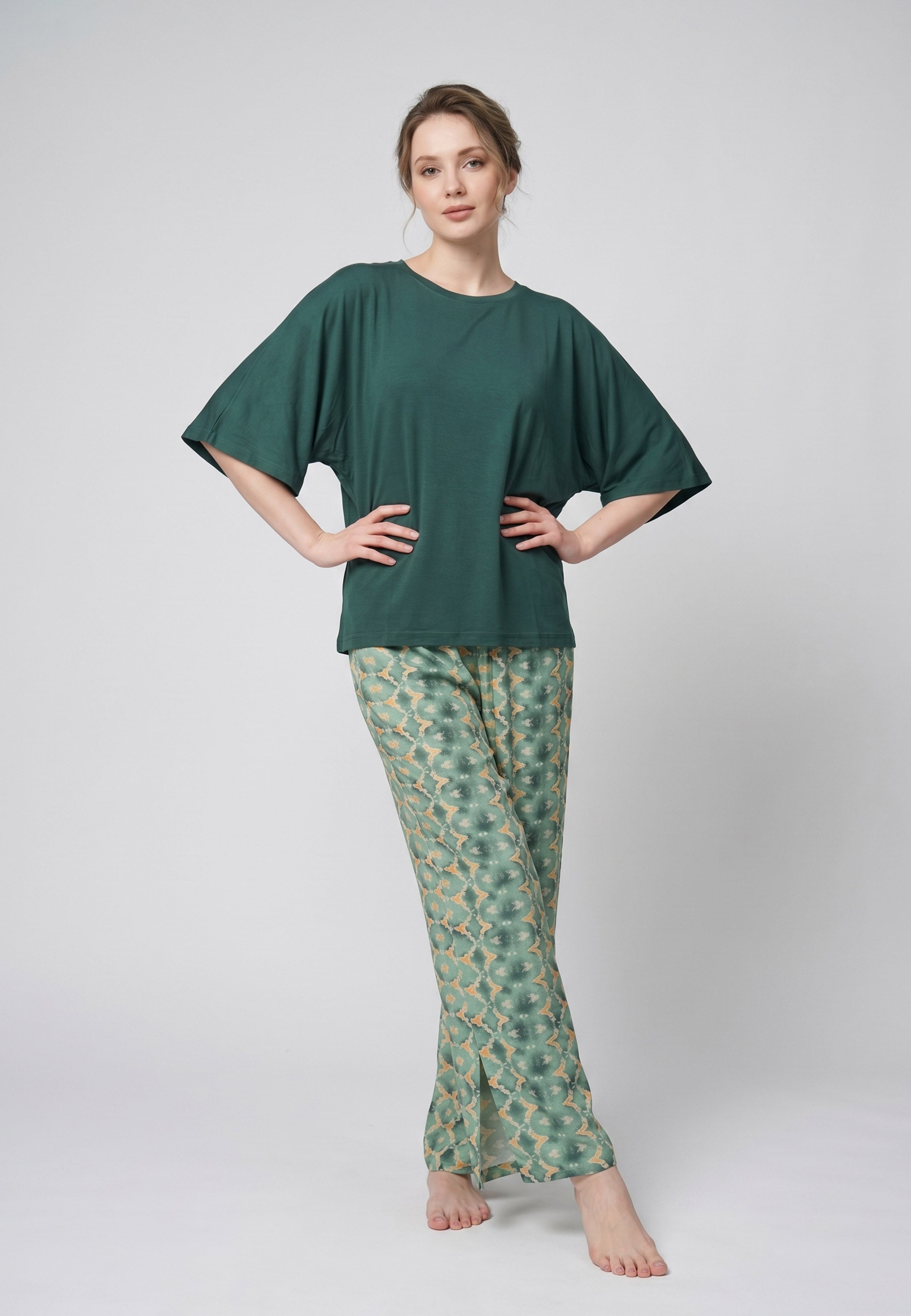 Femme portant un pyjama deux pièces t-shirt oversize uni vert et pantalon large imprimé fleuri blanc sur fond vert Rosabella Cozy Comforts