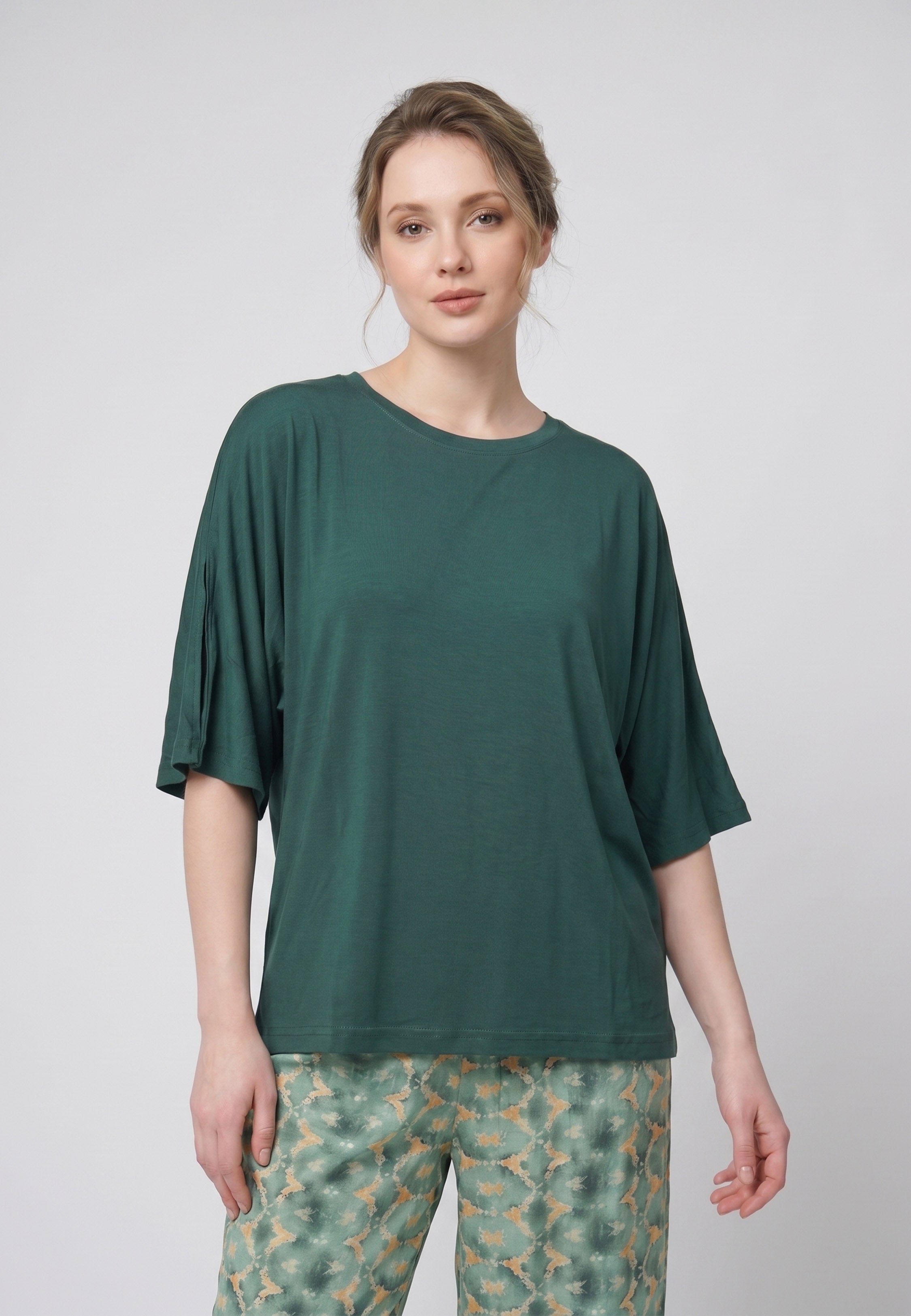 Femme portant un pyjama deux pièces t-shirt oversize uni vert et pantalon large imprimé fleuri blanc sur fond vert Rosabella Cozy Comforts