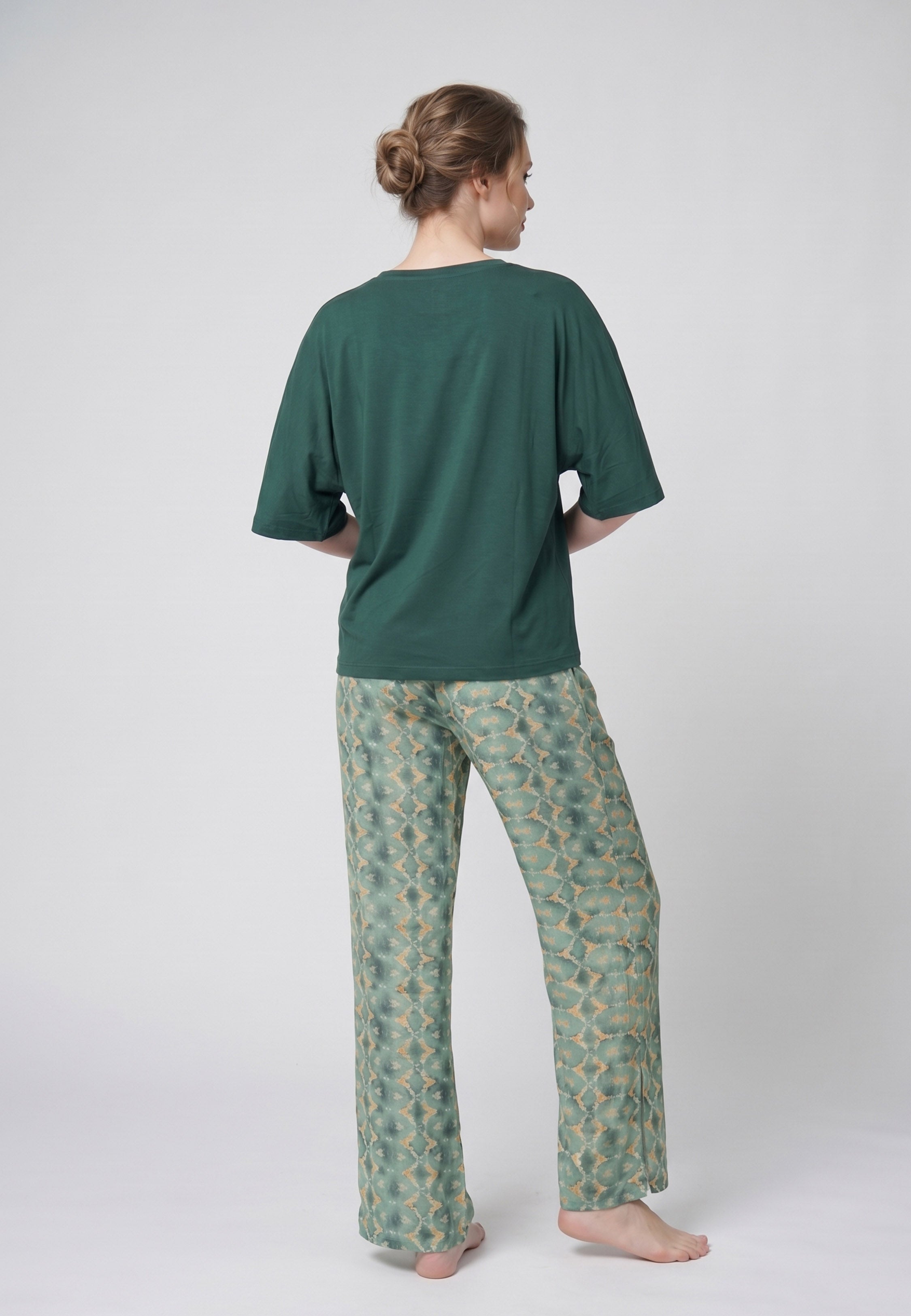 Femme portant un pyjama deux pièces t-shirt oversize uni vert et pantalon large imprimé fleuri blanc sur fond vert Rosabella Cozy Comforts