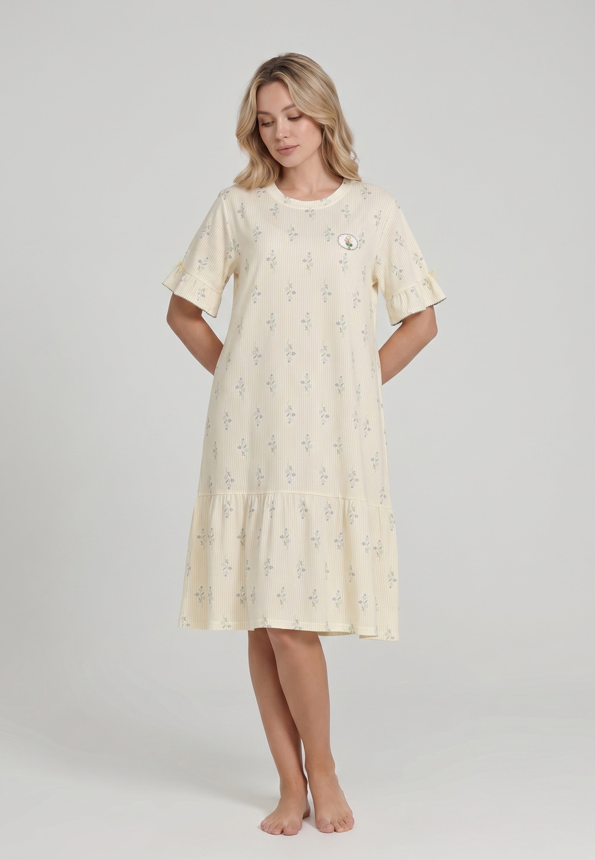 Femme portant une robe de nuit courte col rond manches courtes volantées ourlet volant imprimé rayé fleuri jaune crème à petits motifs floraux bleu badge brodé Rosabella Flowers Scent