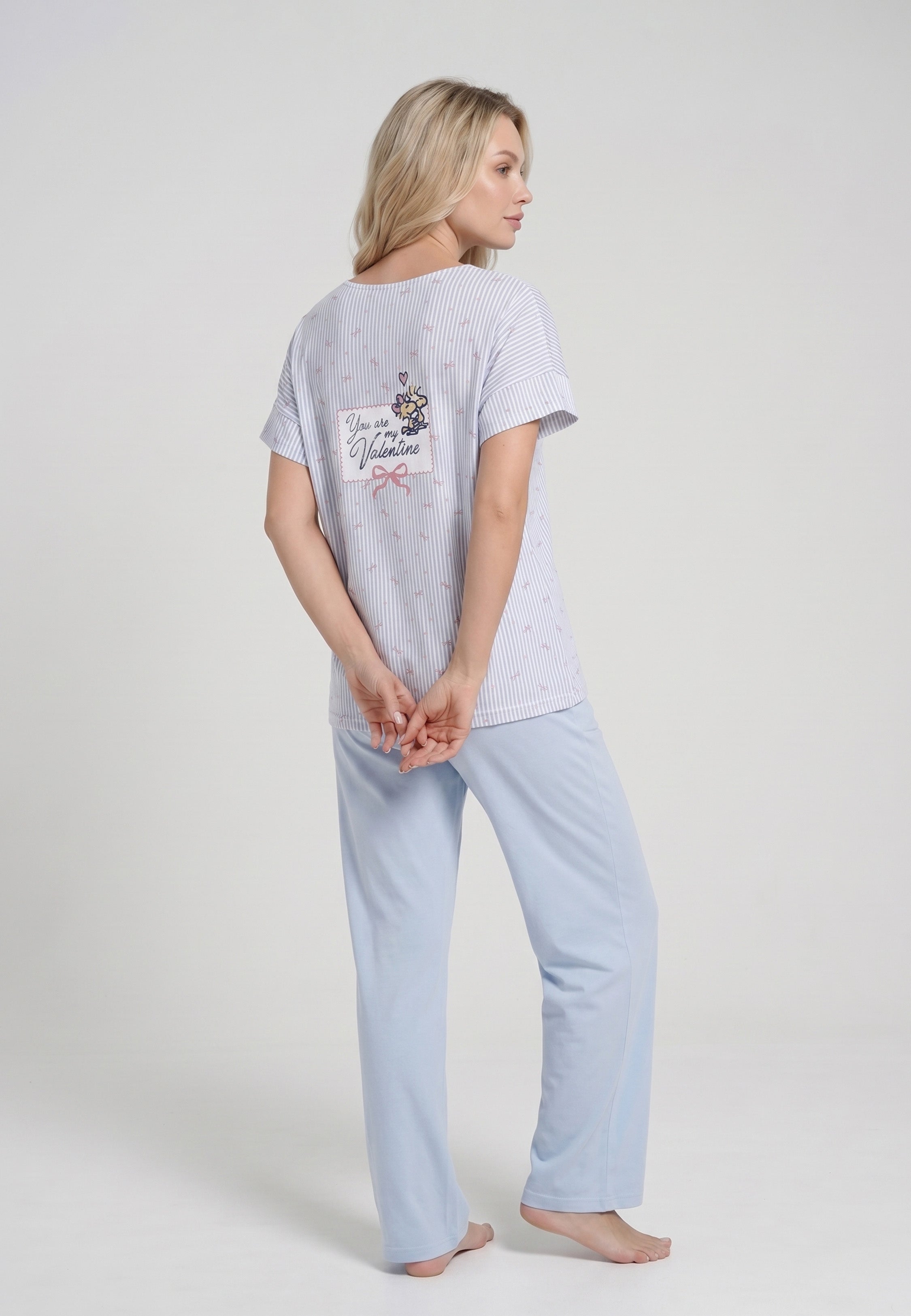 Femme portant un pyjama deux pièces top col V boutonné manches courtes imprimé rayé fleuri bleu ciel et blanc badge brodé et pantalon large uni bleu ciel Rosabella Lina