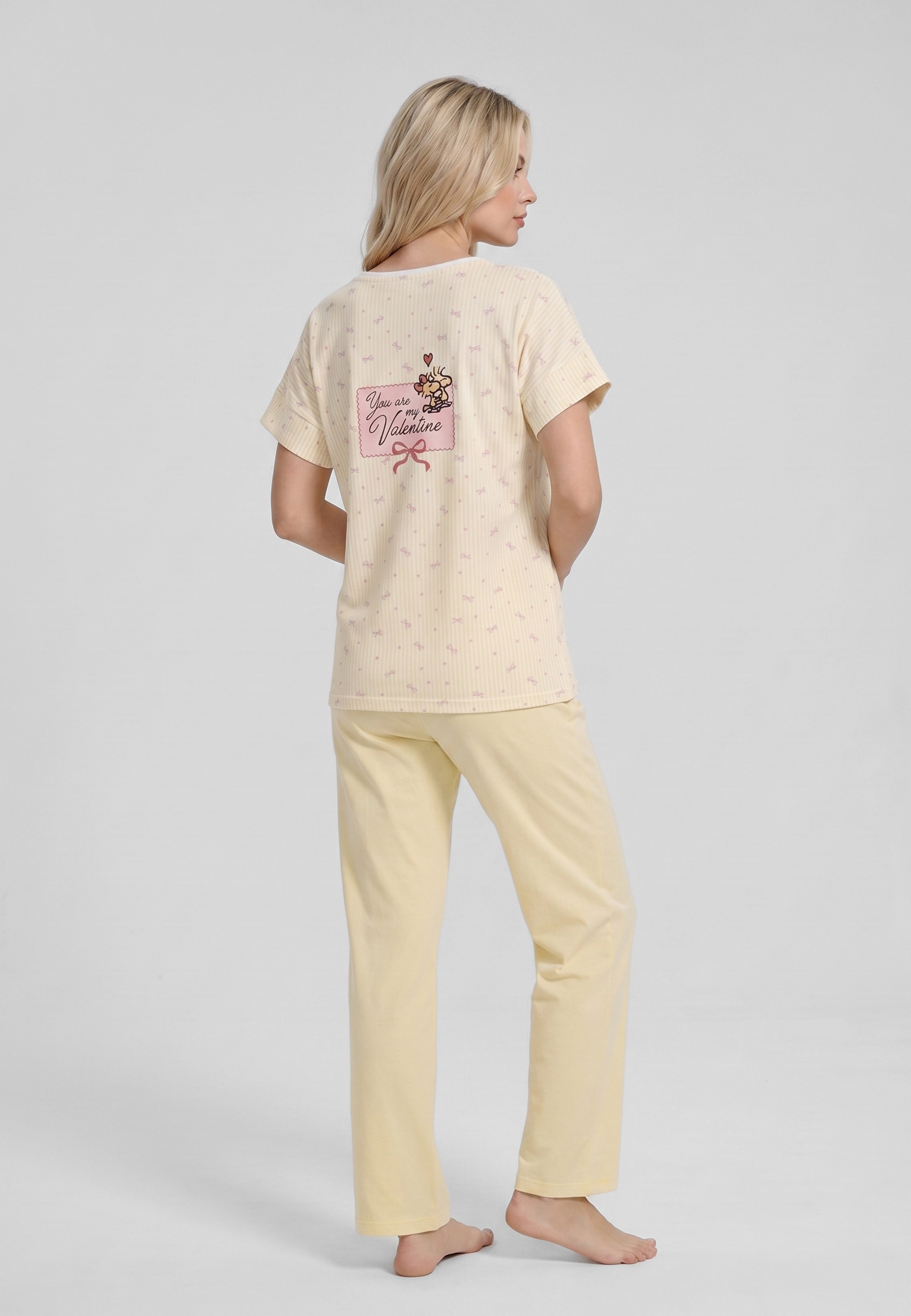 Femme portant un pyjama deux pièces top col V boutonné manches courtes imprimé rayé fleuri jaune et blanc badge brodé et pantalon large uni jaune Rosabella Lina