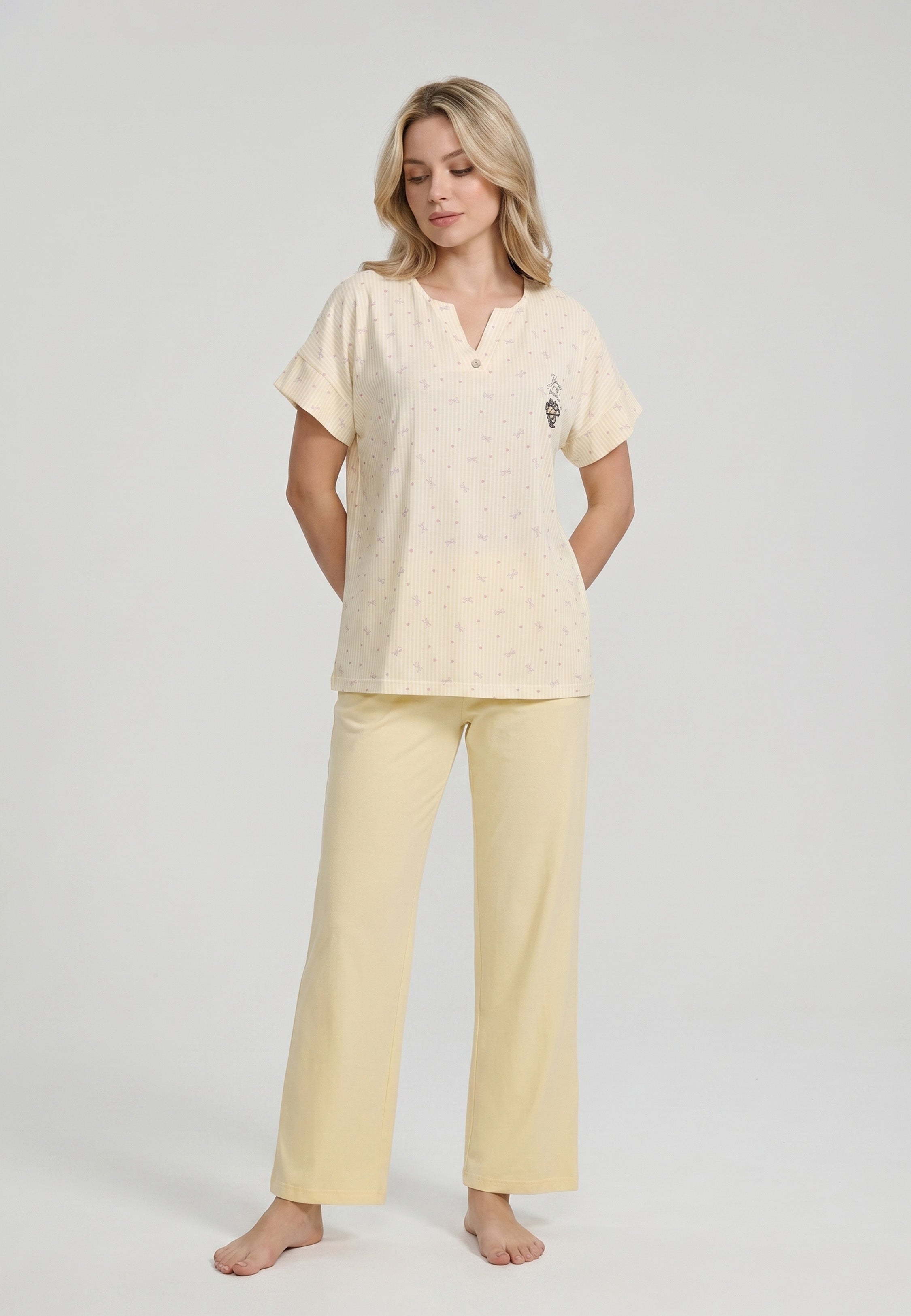 Femme portant un pyjama deux pièces top col V boutonné manches courtes imprimé rayé fleuri jaune et blanc badge brodé et pantalon large uni jaune Rosabella Lina
