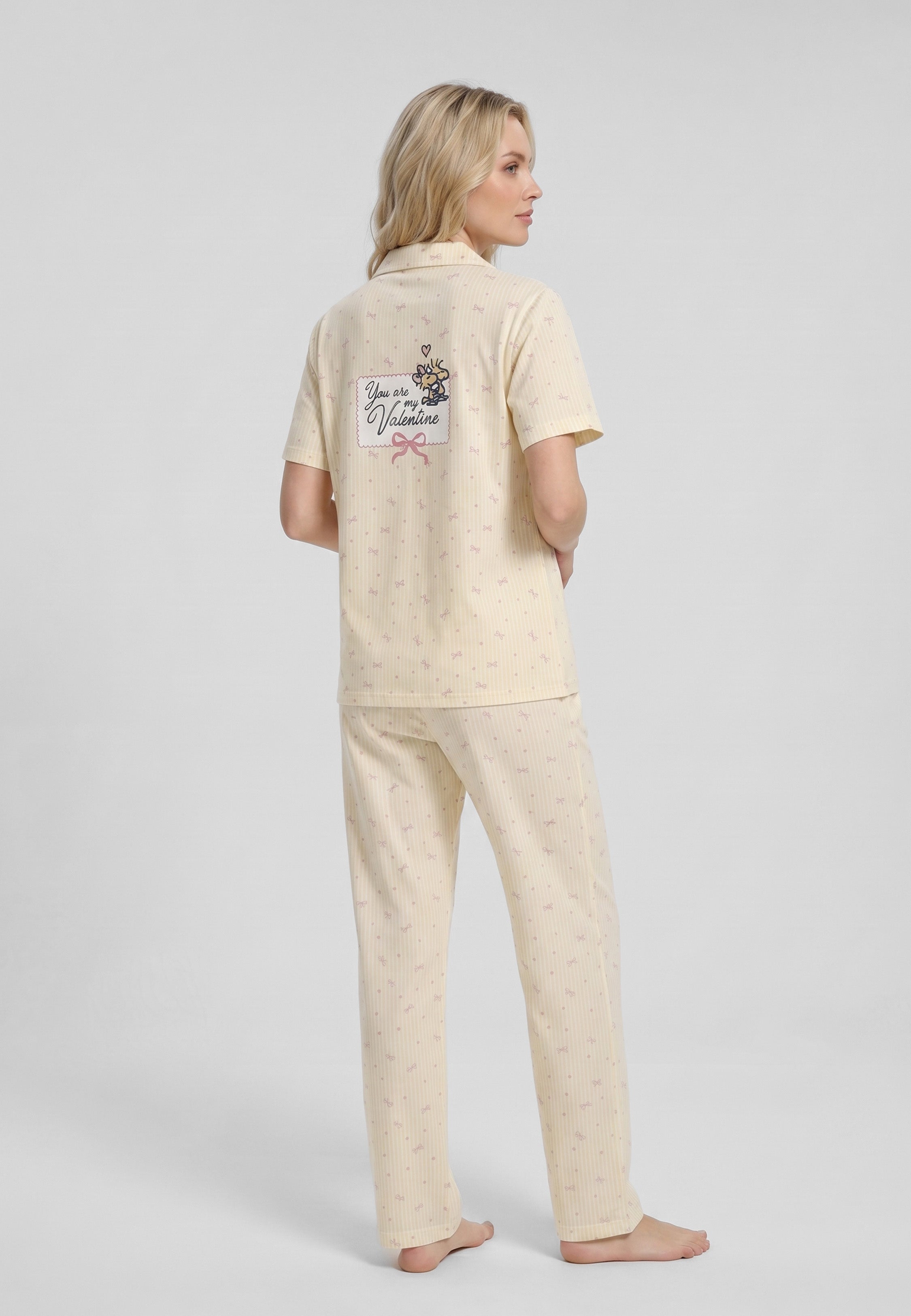 Femme portant un pyjama deux pièces chemise boutonnée col pyjama à revers manches courtes imprimé rayé fleuri jaune et blanc badge brodé et pantalon droit assorti Rosabella Lina