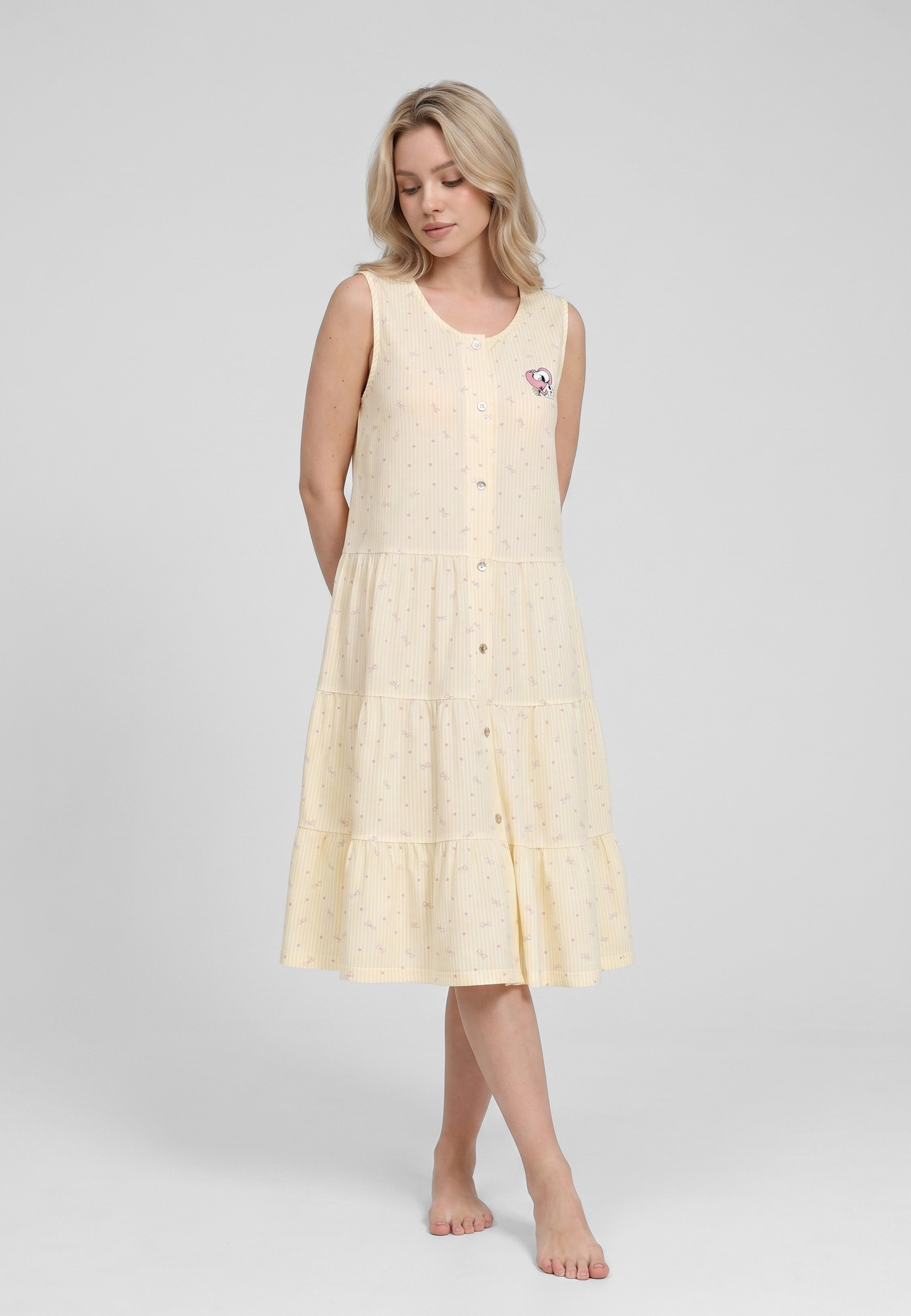 Femme portant une robe de nuit midi boutonnée sans manches imprimé rayé fleuri jaune et blanc à petits motifs floraux badge brodé ourlet volants étagés Rosabella Lina
