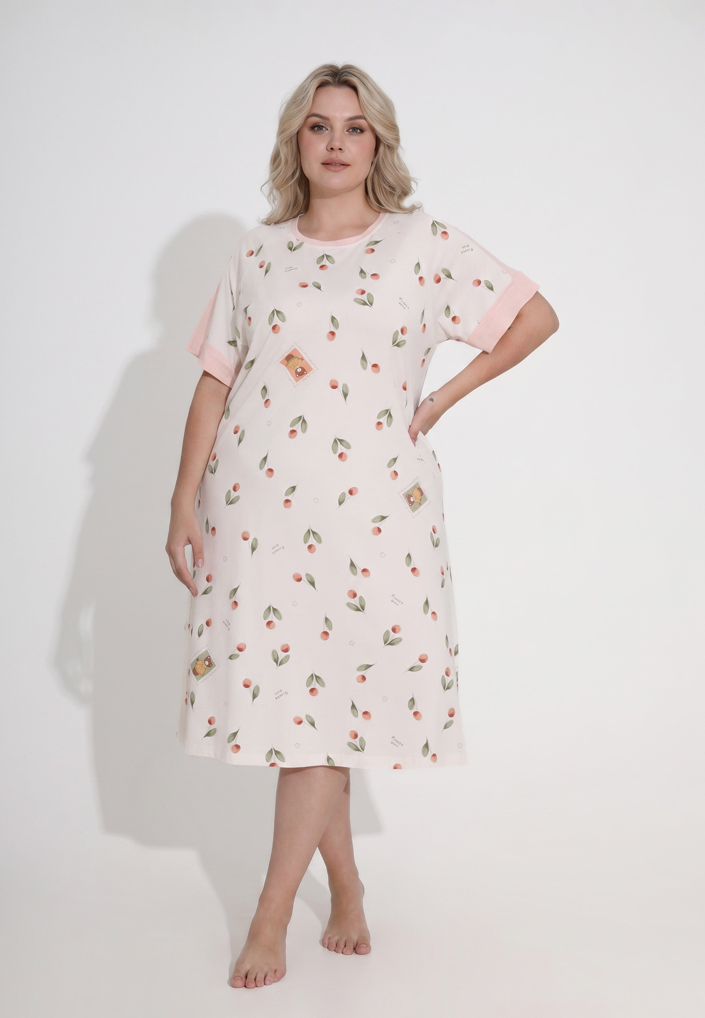 Femme portant une robe de nuit midi col rond manches courtes imprimé cerises et pêches aquarelle fond crème parements contrastants rose Rosabella Douceur Cerise