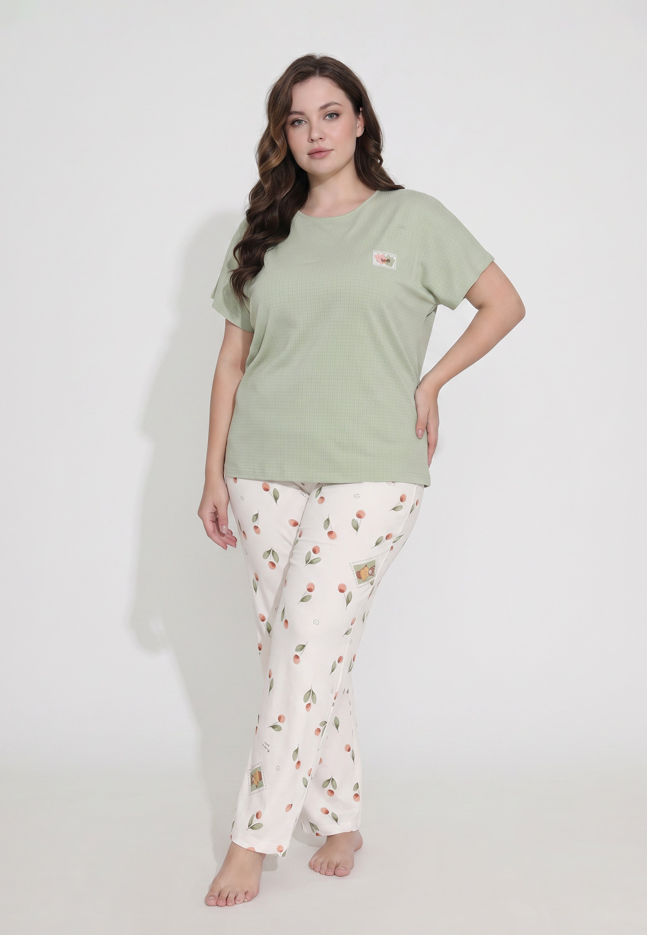 Femme portant un pyjama top col rond manches courtes texturé uni kaki badge brodé et pantalon droit imprimé cerises et pêches aquarelle fond crème Rosabella Douceur Cerise