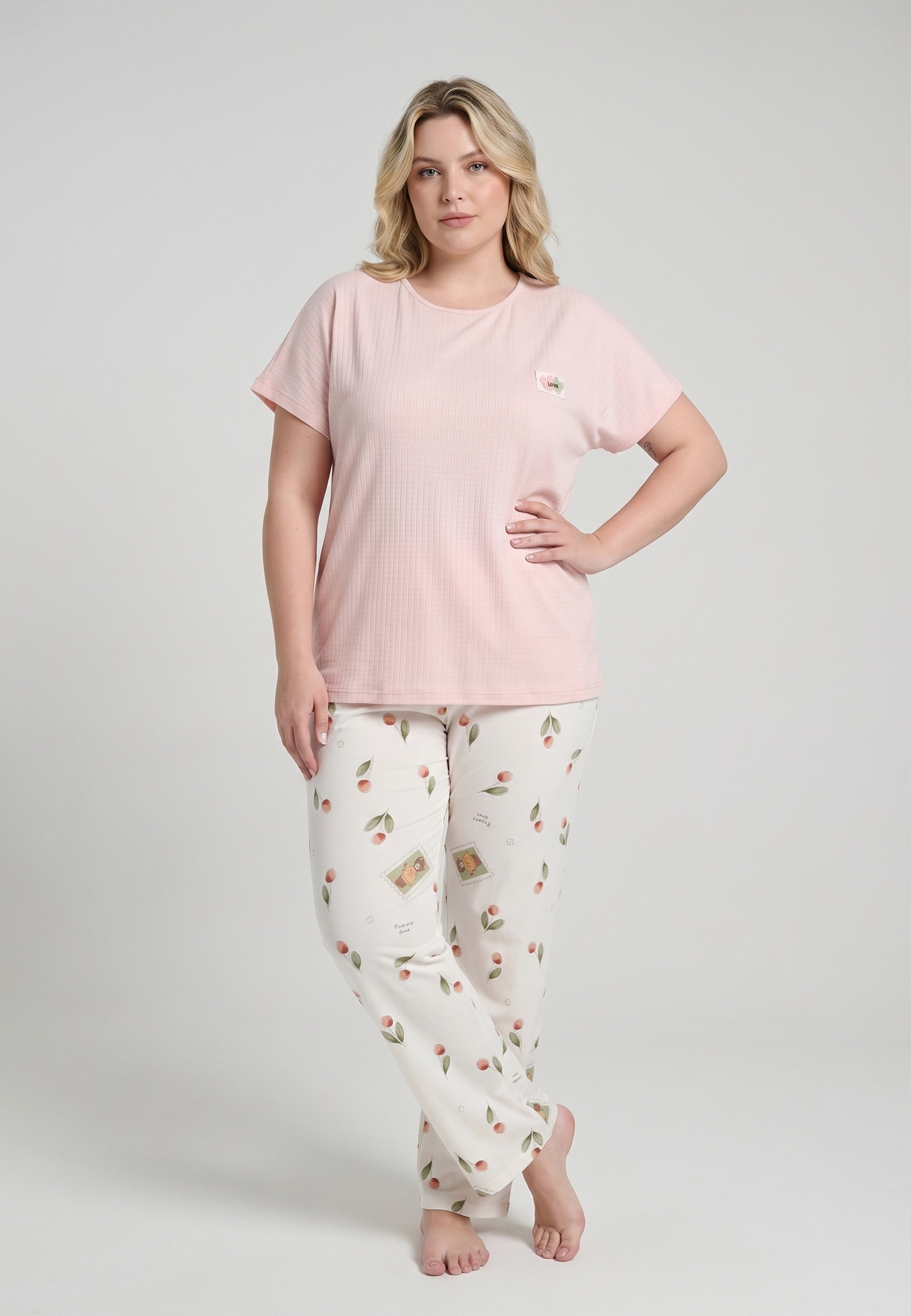 Femme portant un pyjama top col rond manches courtes texturé uni rose badge brodé et pantalon droit imprimé cerises et pêches aquarelle fond crème Rosabella Douceur Cerise