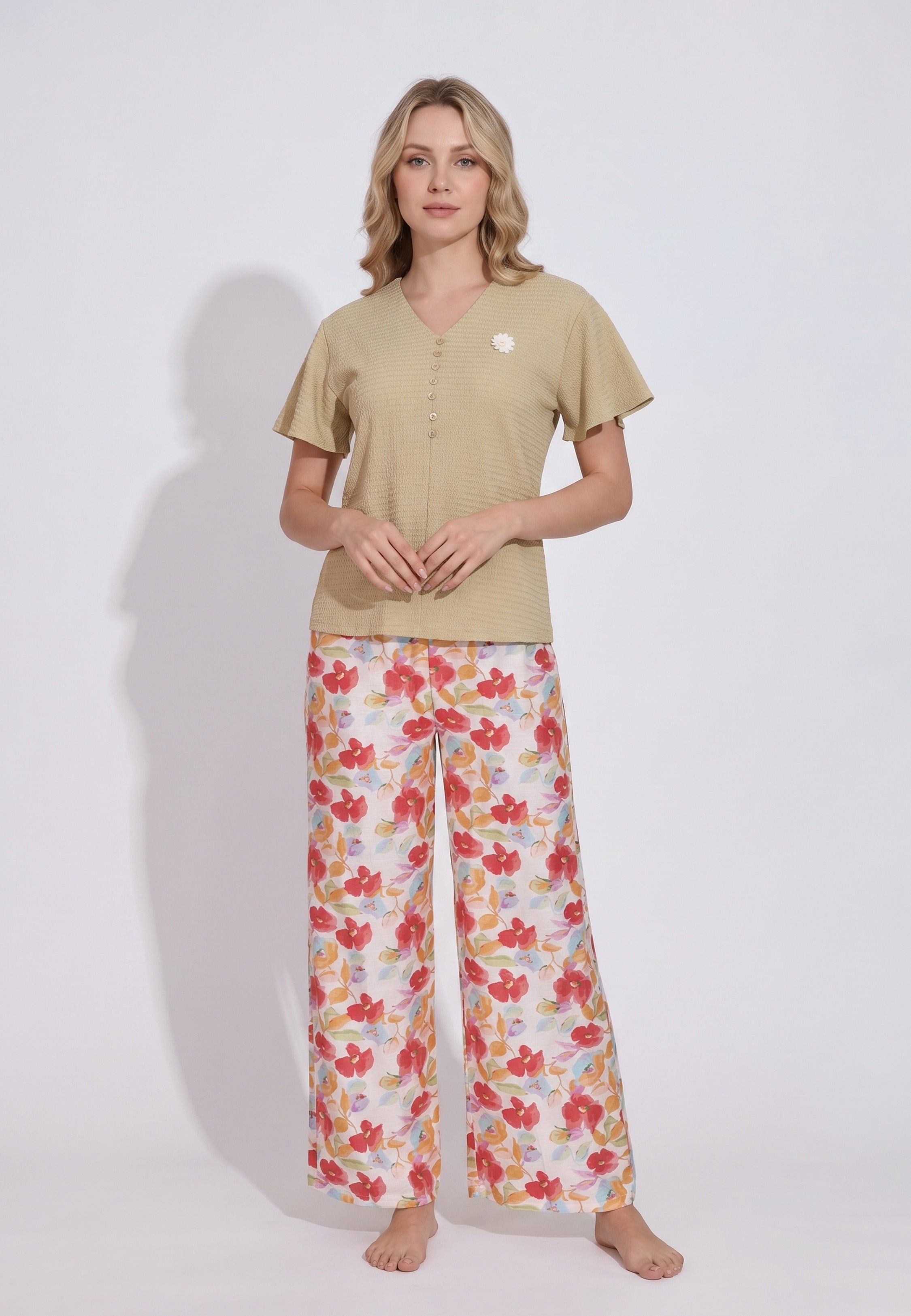 Femme portant un pyjama top col V boutonné manches volantées texturé uni moutarde foncé badge marguerite brodé et pantalon large grand imprimé fleuri aquarelle multicolore fond blanc Rosabella Rosy Mood