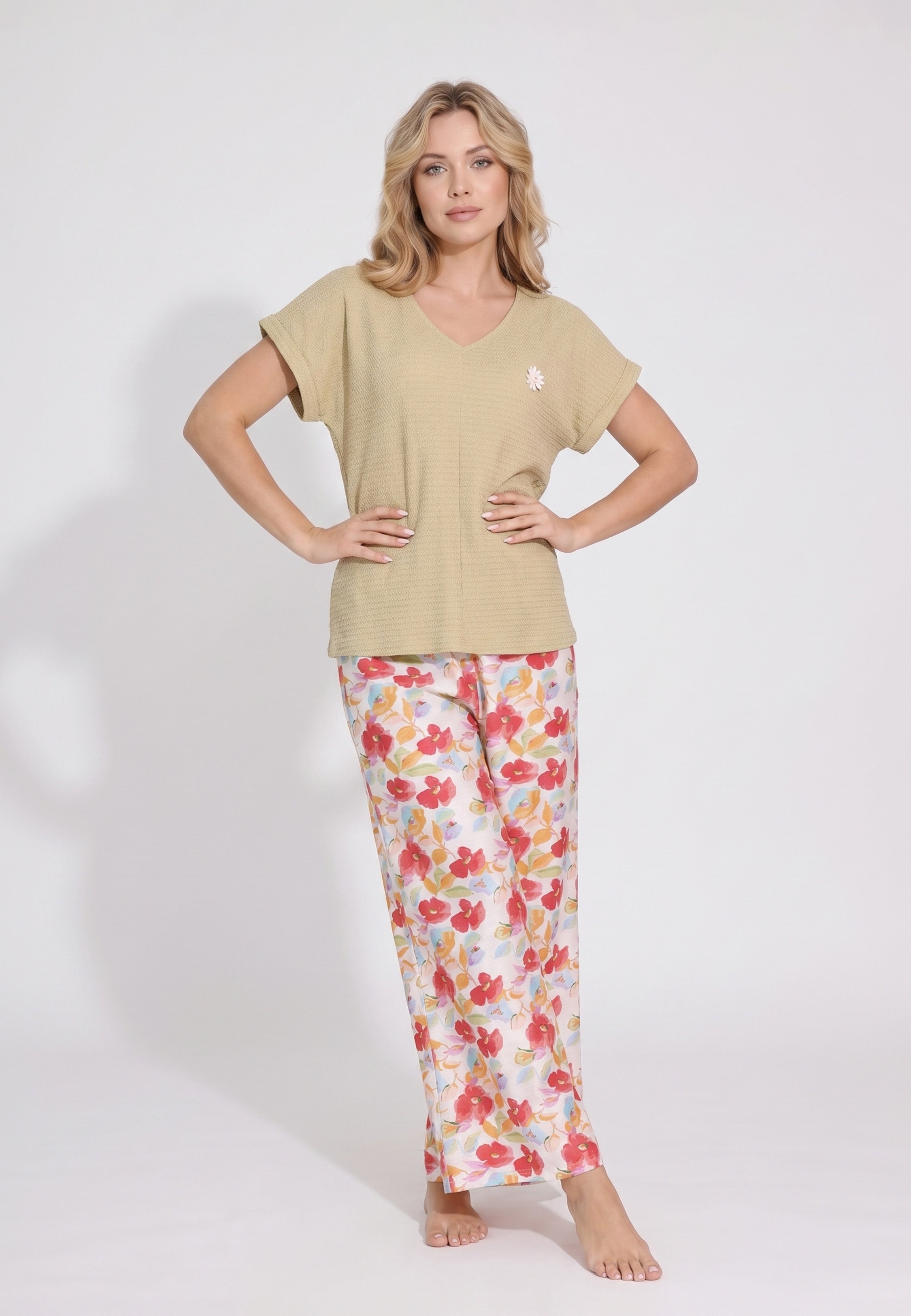 Femme portant un pyjama top col V évasé manches courtes tombantes uni moutarde foncé badge marguerite brodé et pantalon large grand imprimé fleuri aquarelle multicolore fond blanc Rosabella Rosy Mood