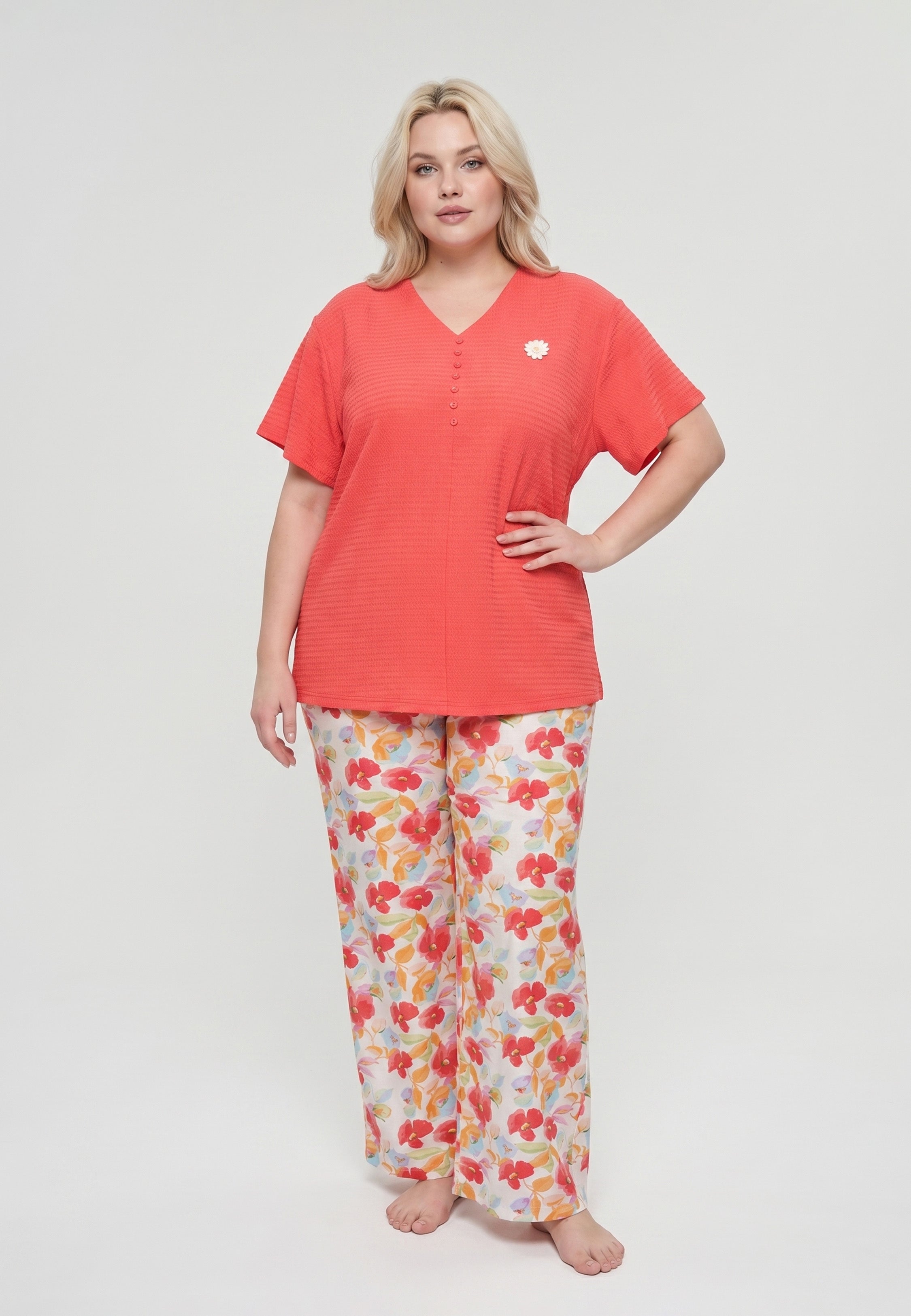 Femme portant un pyjama top col V boutonné manches courtes texturé uni corail badge marguerite brodé et pantalon large grand imprimé fleuri aquarelle multicolore fond blanc Rosabella Rosy Mood