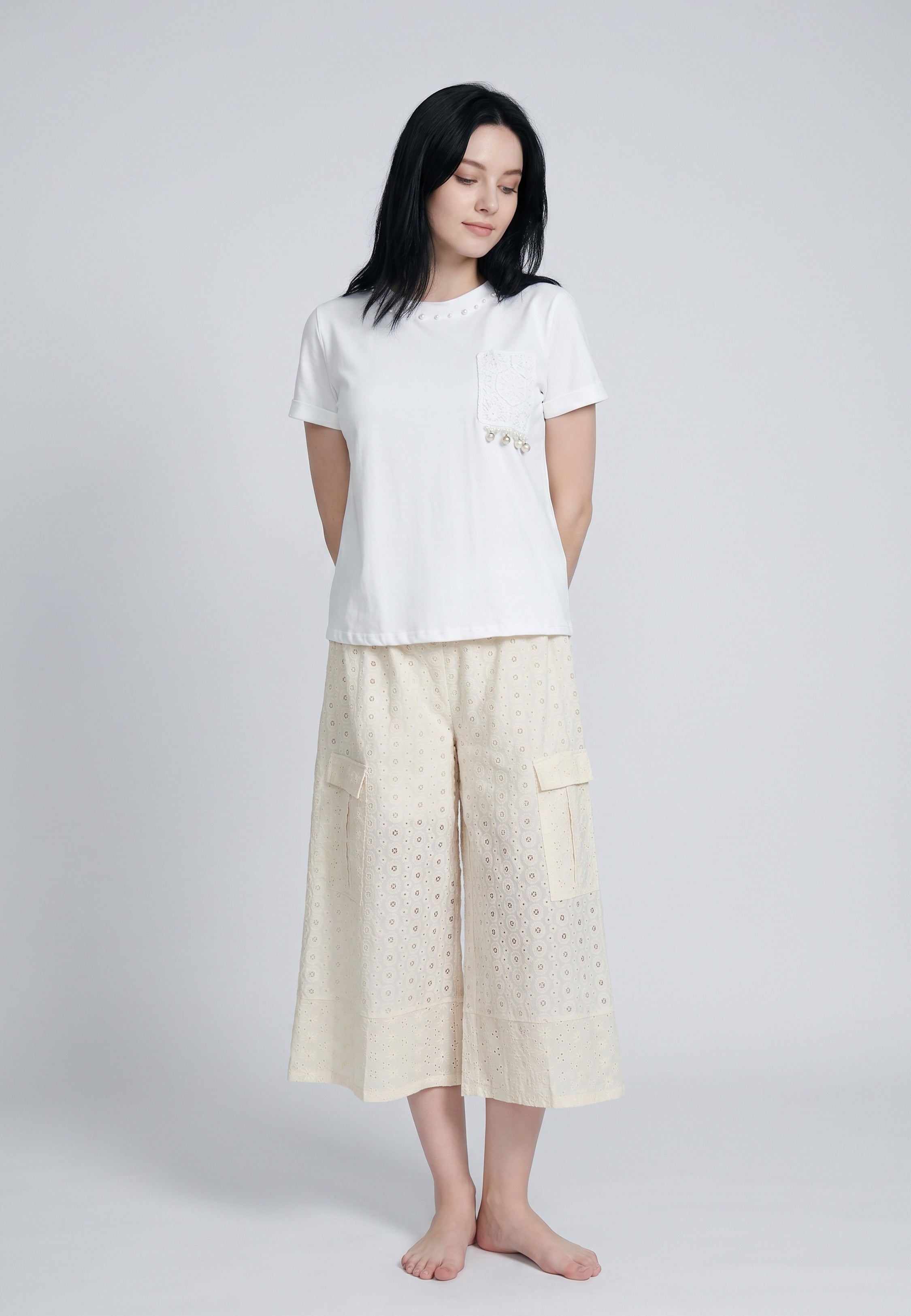 Femme portant un ensemble top col rond blanc poche broderie anglaise perles glands et culottes larges ivoire broderie anglaise poches cargo Rosabella