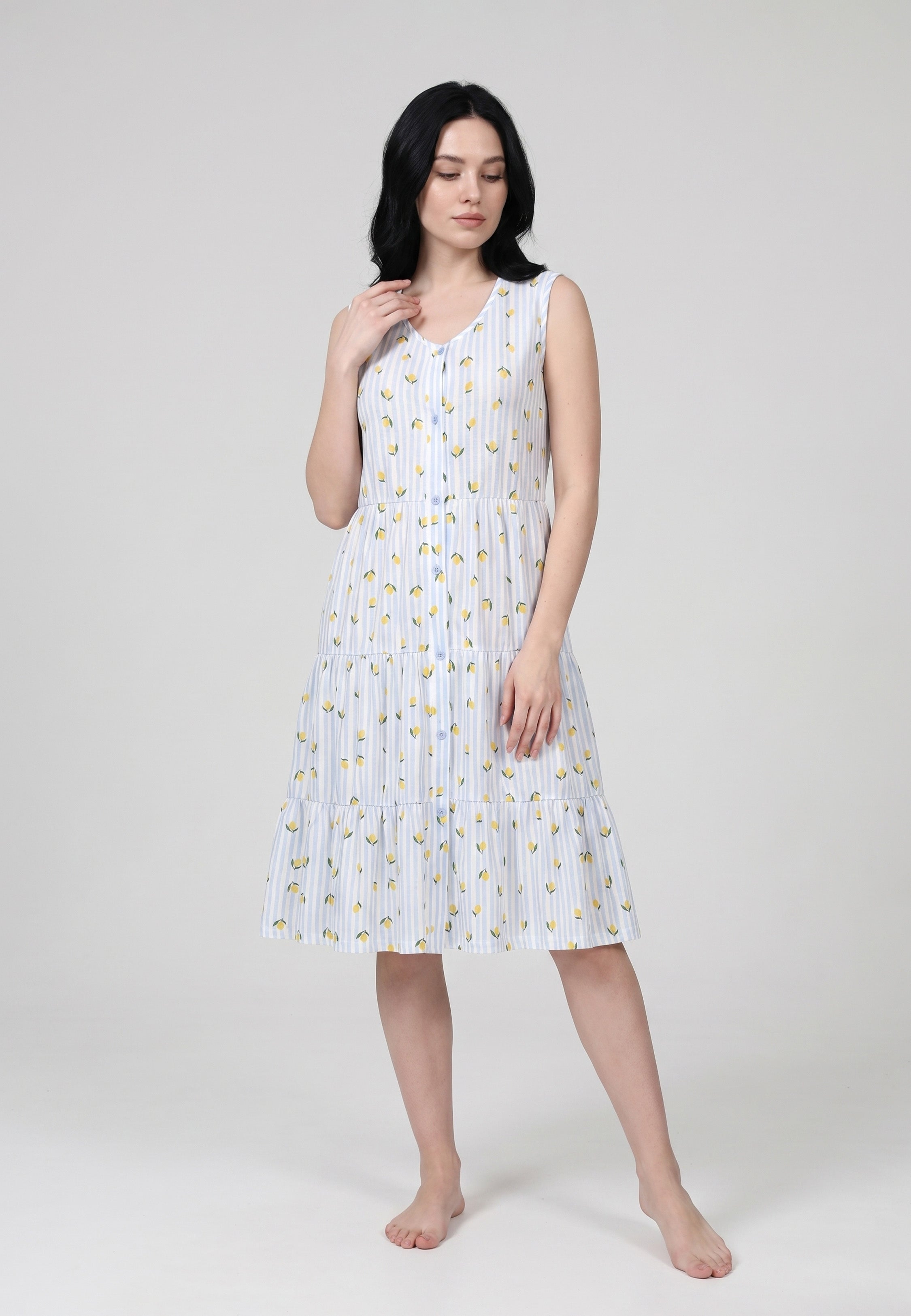 Femme portant une robe pyjama sans manches col V boutonné fond blanc rayé bleu ciel imprimée petits citrons jupe étagée Rosabella