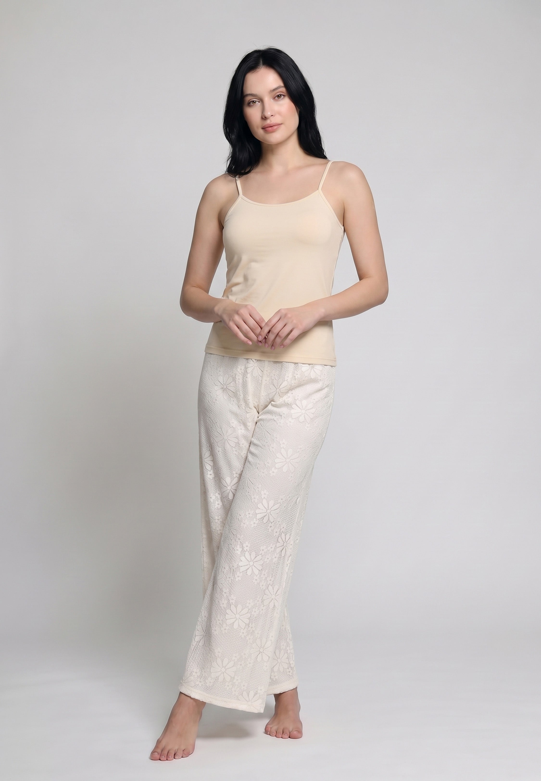 Femme portant un ensemble caraco à bretelles fines sable nude et pantalon large dentelle florale ivoire transparente motif marguerites Rosabella