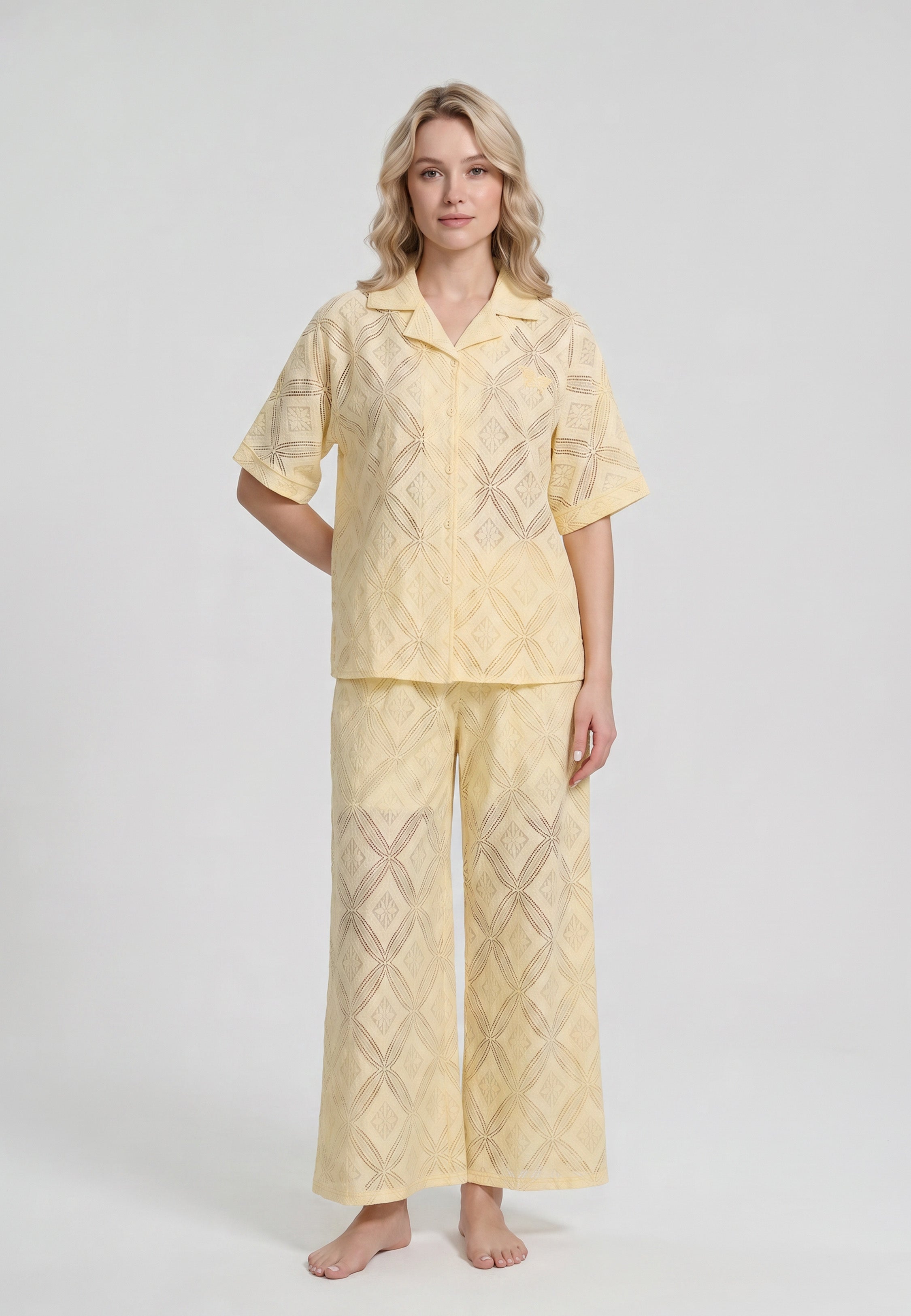 Femme portant un ensemble chemise camp boutonnée manches courtes et pantalon large broderie anglaise ajourée géométrique jaune beurre Rosabella