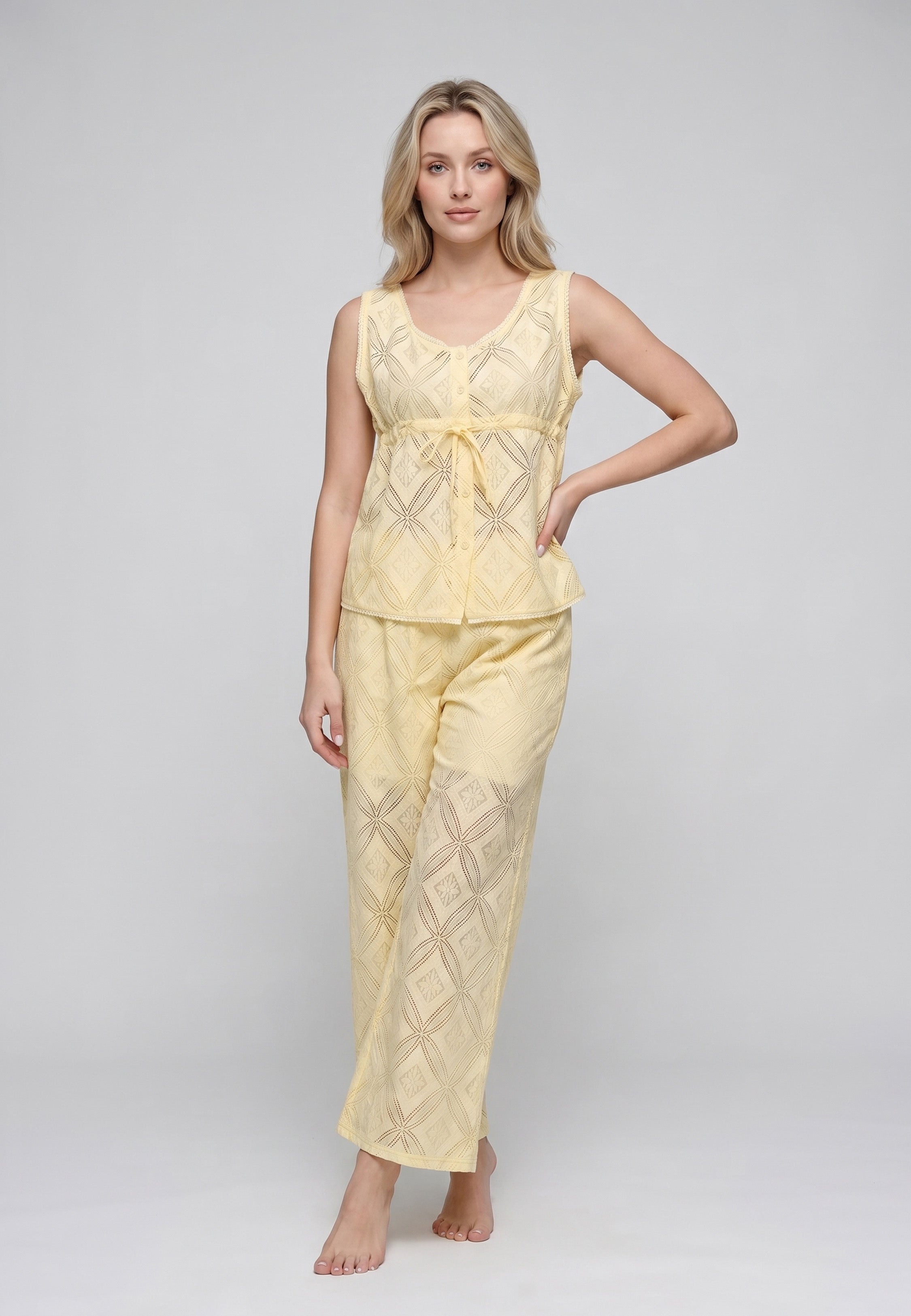 Femme portant un ensemble débardeur col rond noué broderie anglaise ajourée géométrique jaune beurre et pantalon large assorti Rosabella