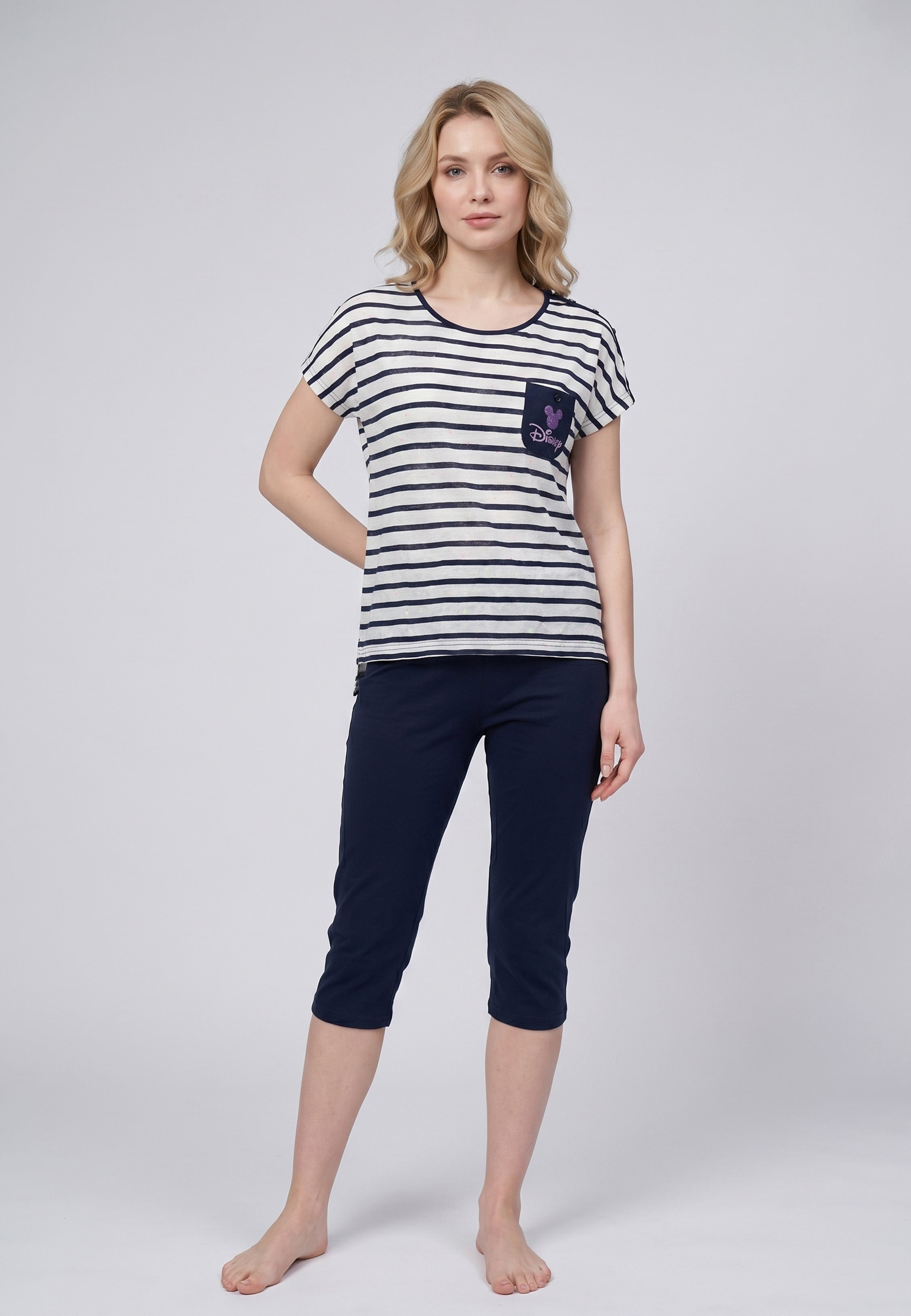 Femme portant un pyjama deux pièces rayé marine avec poche poitrine Disney pailletée et corsaire uni bleu marine
