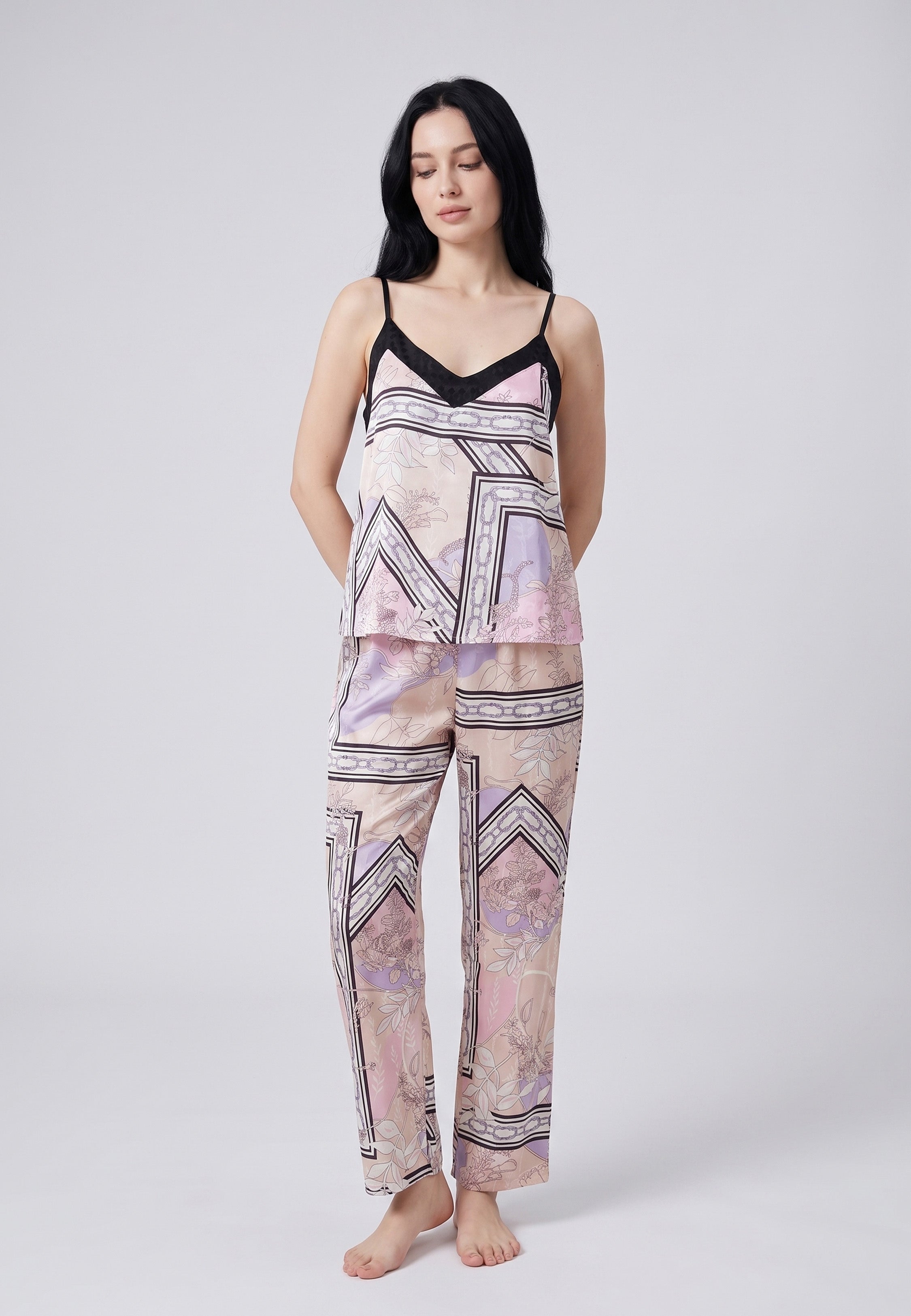Femme portant un pyjama deux pièces caraco à bretelles fines et pantalon long en satin imprimé foulard rose poudré et lilas Rosabella