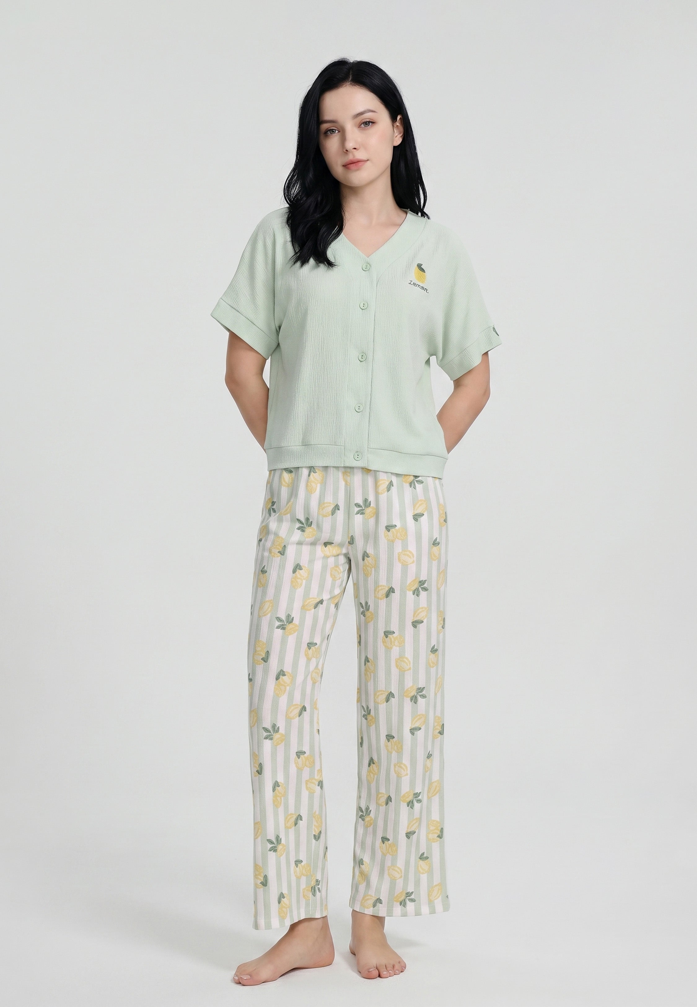 Femme portant un ensemble loungewear top col V boutonné uni vert menthe badge brodé citron et pantalon large wide-leg rayures vert blanc imprimé citrons jaunes Rosabella