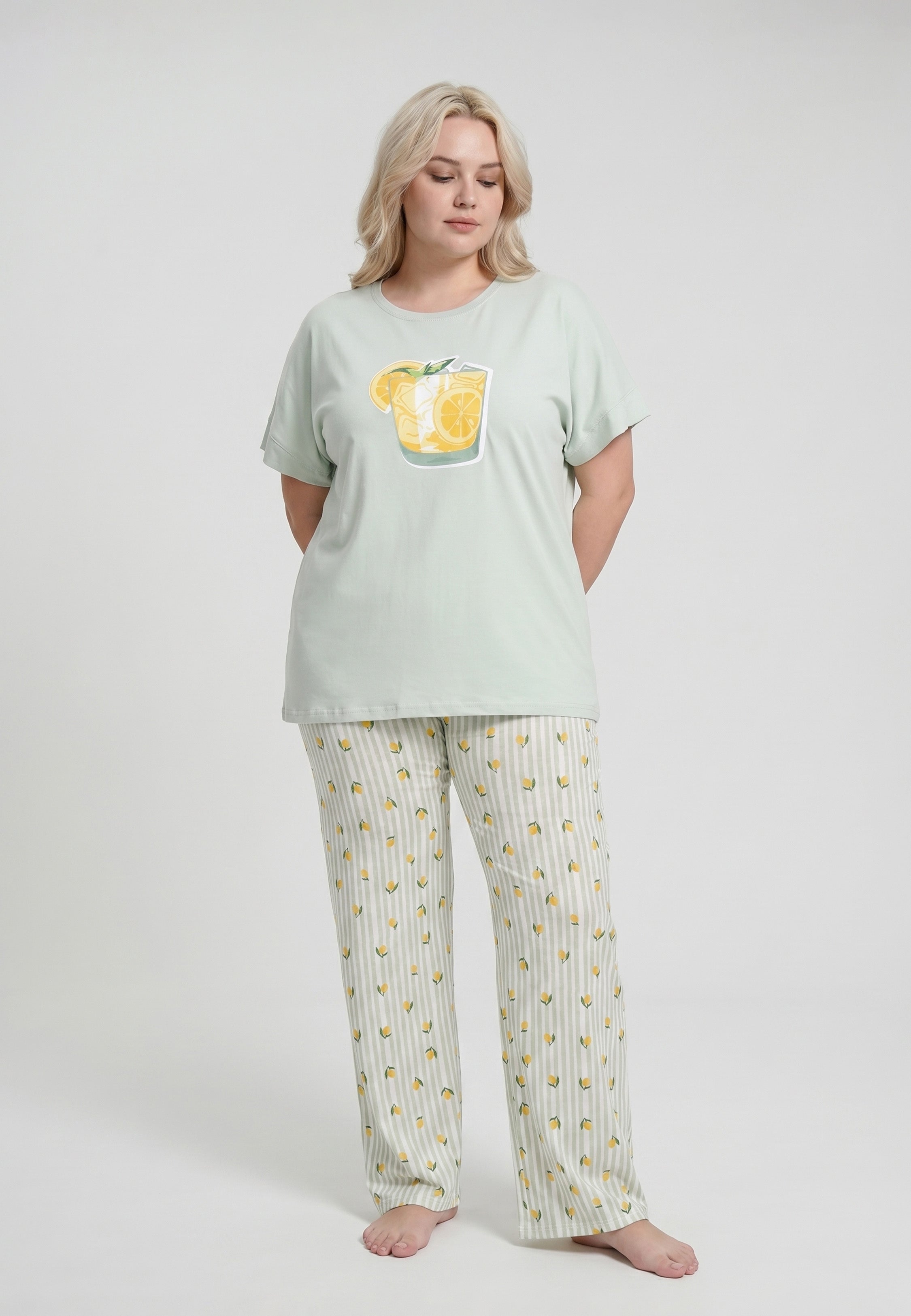 Femme portant un pyjama grande taille t-shirt vert sauge grand badge citronnade et pantalon rayé vert sauge blanc imprimé petits citrons Rosabella