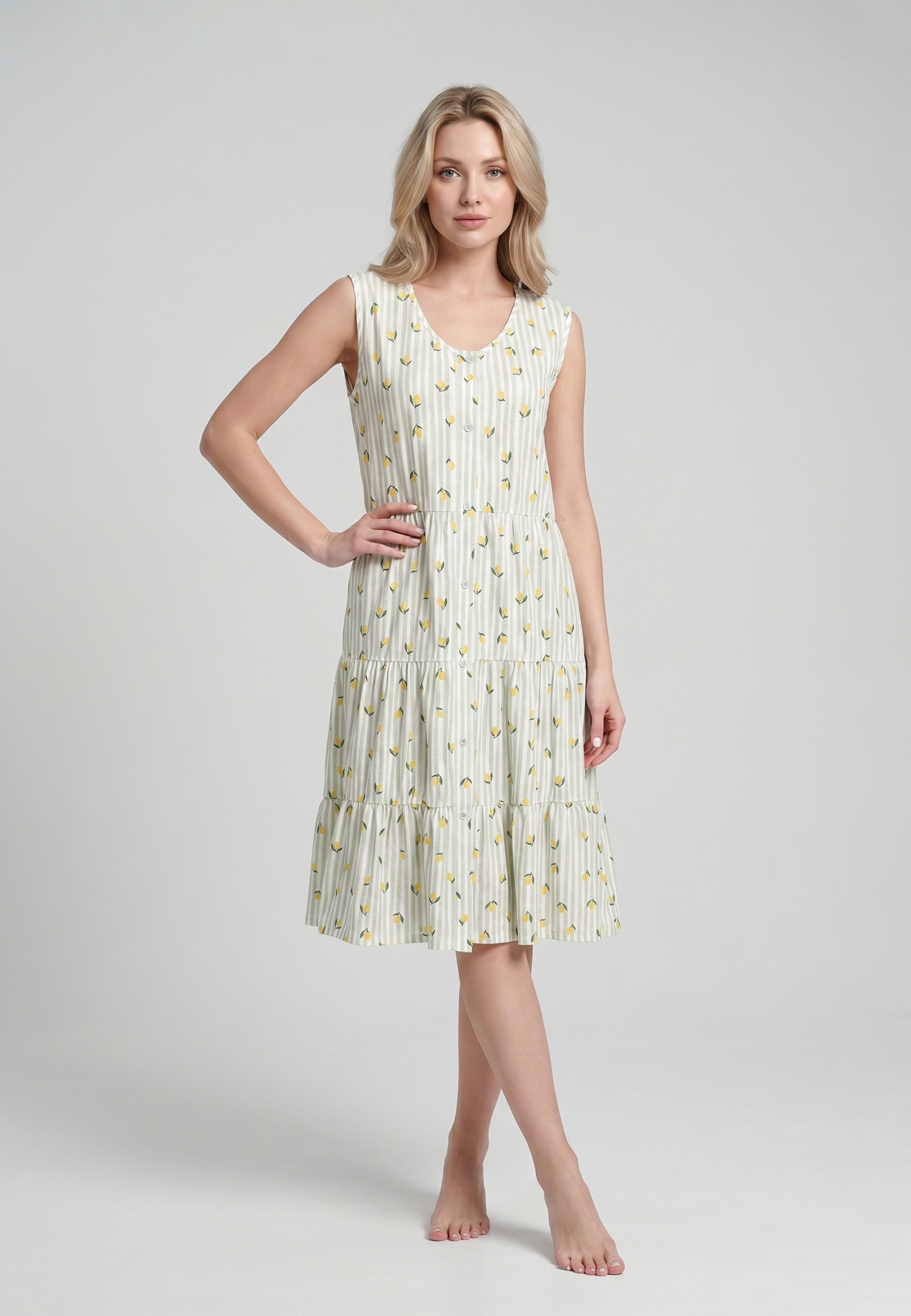 Femme portant une robe pyjama sans manches col V boutonné fond blanc rayé vert sauge imprimée petits citrons jupe étagée Rosabella