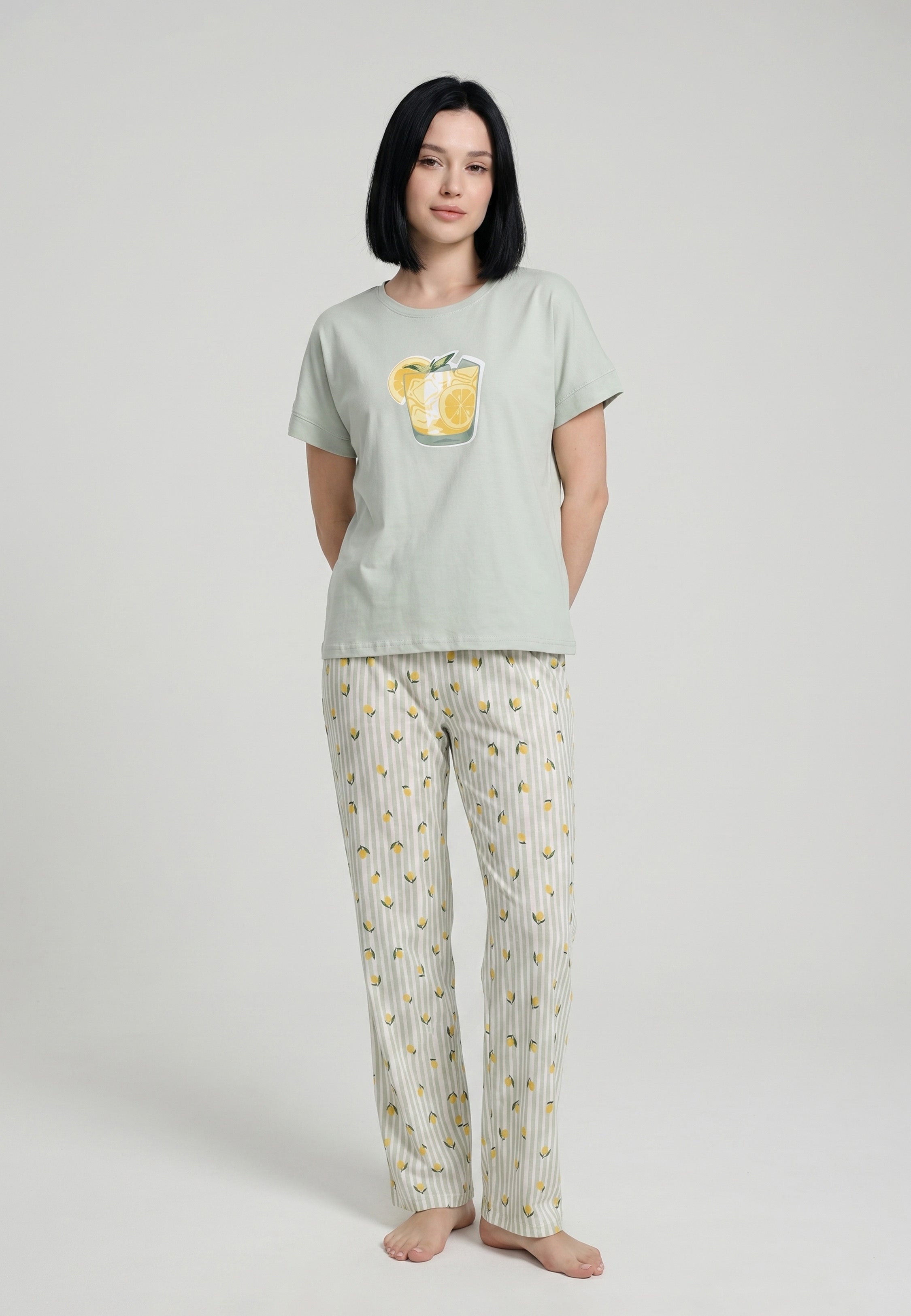 Femme portant un pyjama t-shirt manches courtes vert sauge grand badge citronnade et pantalon rayé vert sauge blanc imprimé petits citrons Rosabella