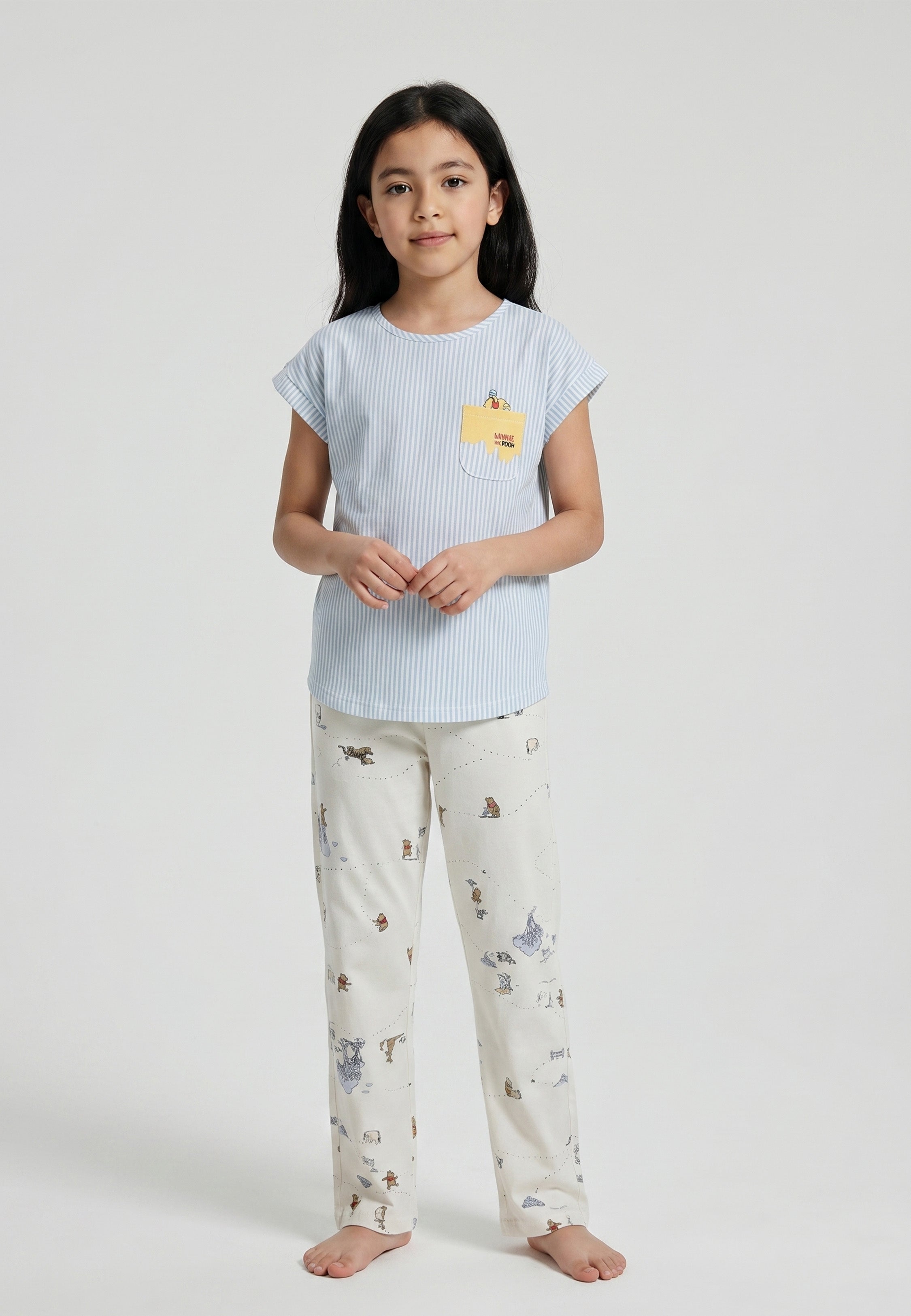 Enfant portant un ensemble pyjama top col rond seersucker rayé bleu ciel poche patchée et pantalon imprimé fond crème Rosabella
