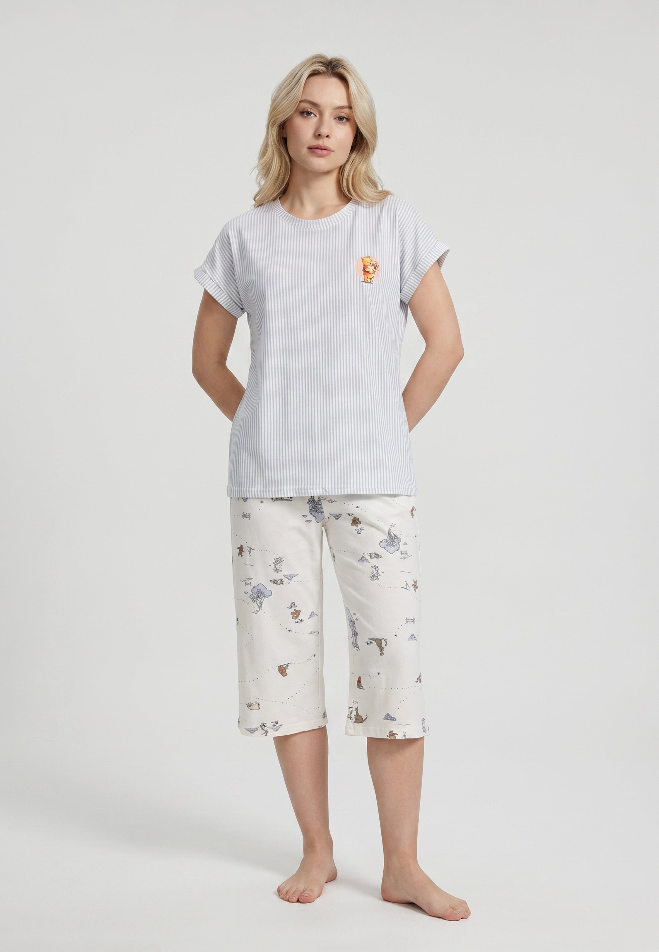 Femme portant un ensemble pyjama top col rond seersucker rayé bleu ciel badge et pantacourt imprimé all-over fond crème Rosabella