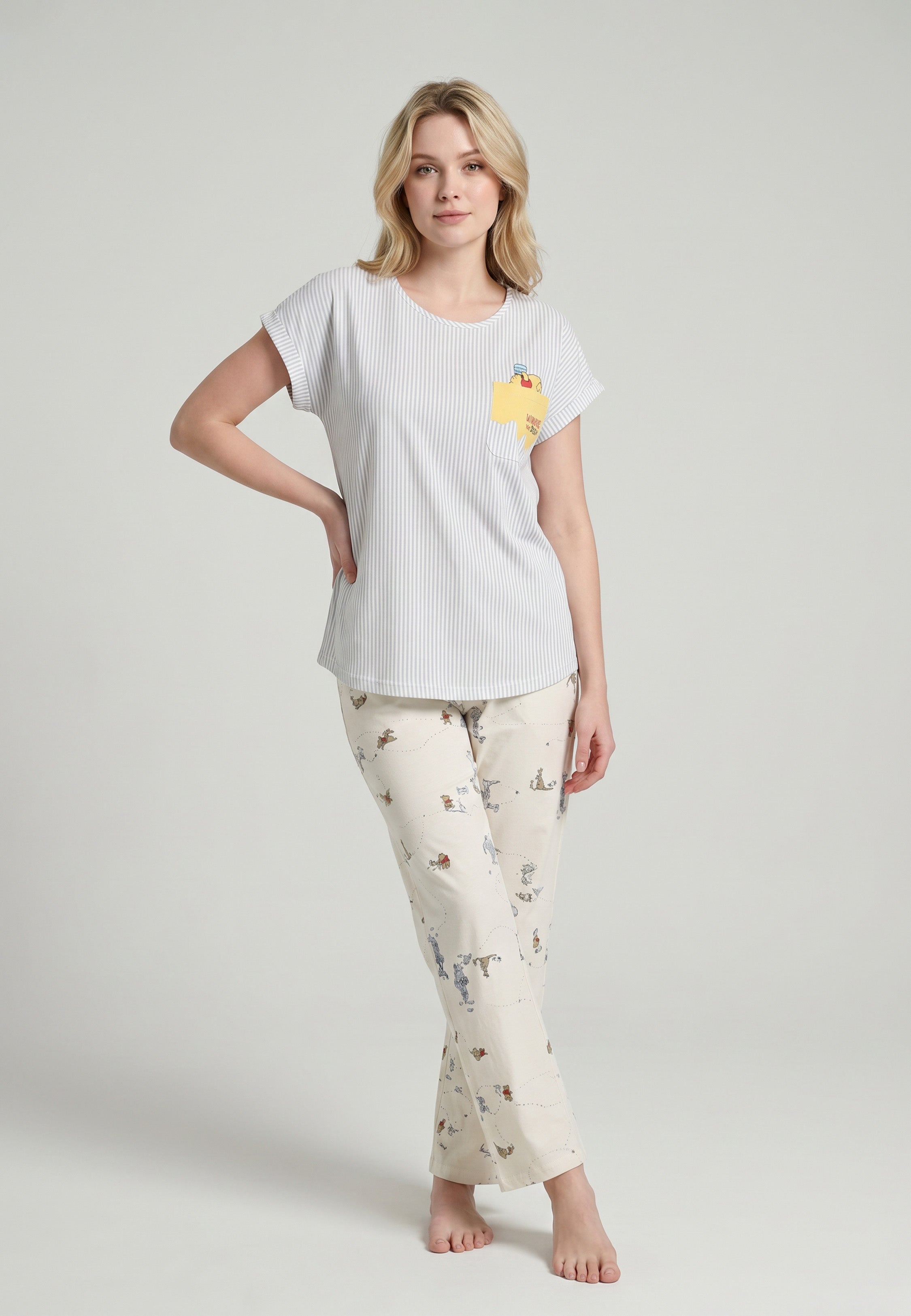 Femme portant un ensemble pyjama top col V seersucker rayé bleu ciel poche patchée et pantalon imprimé all-over fond crème Rosabella