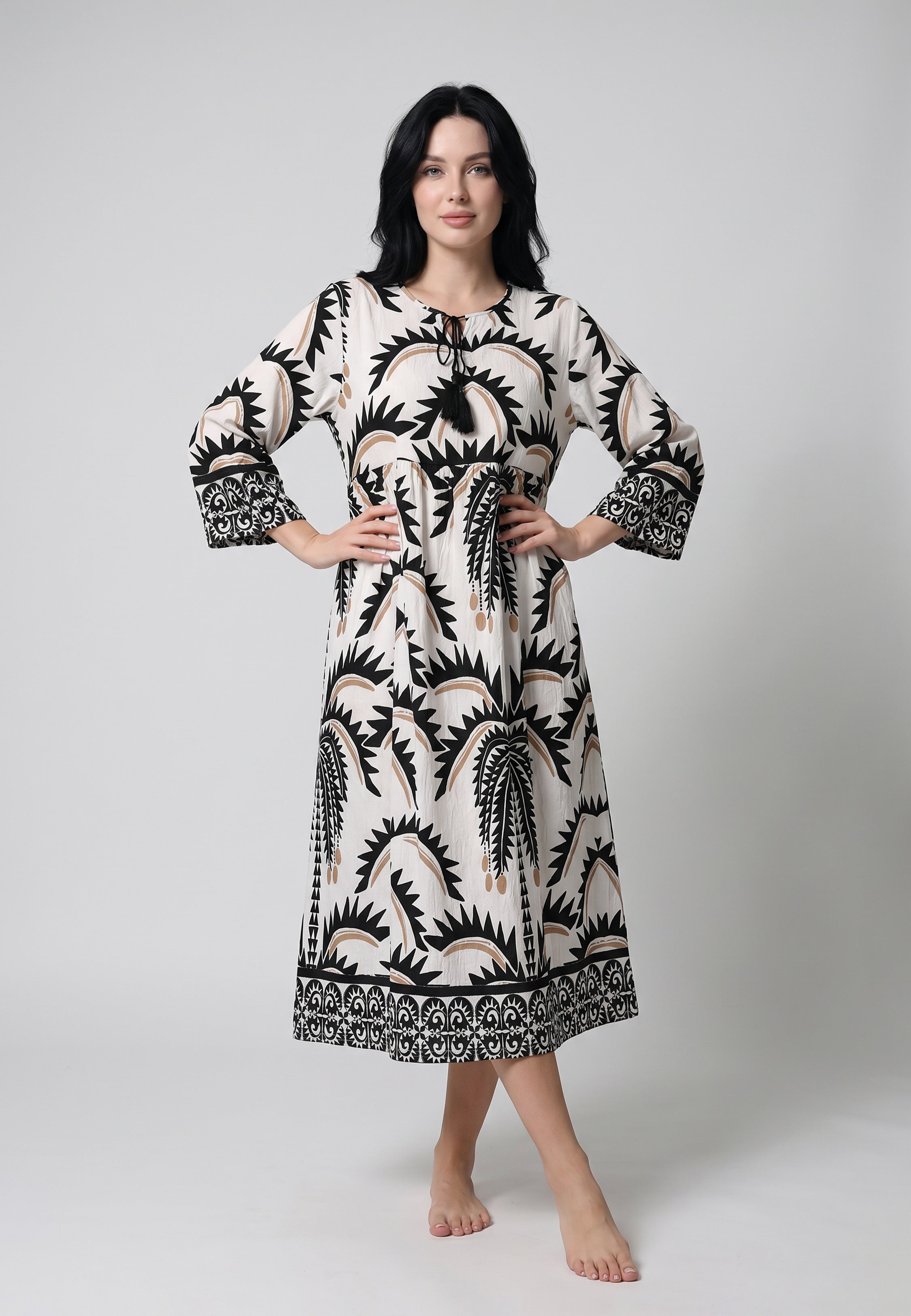 Femme portant une robe midi manches 3/4 imprimée grands palmiers tribaux ivoire crème camel fond blanc bordure géométrique ethnique Rosabella