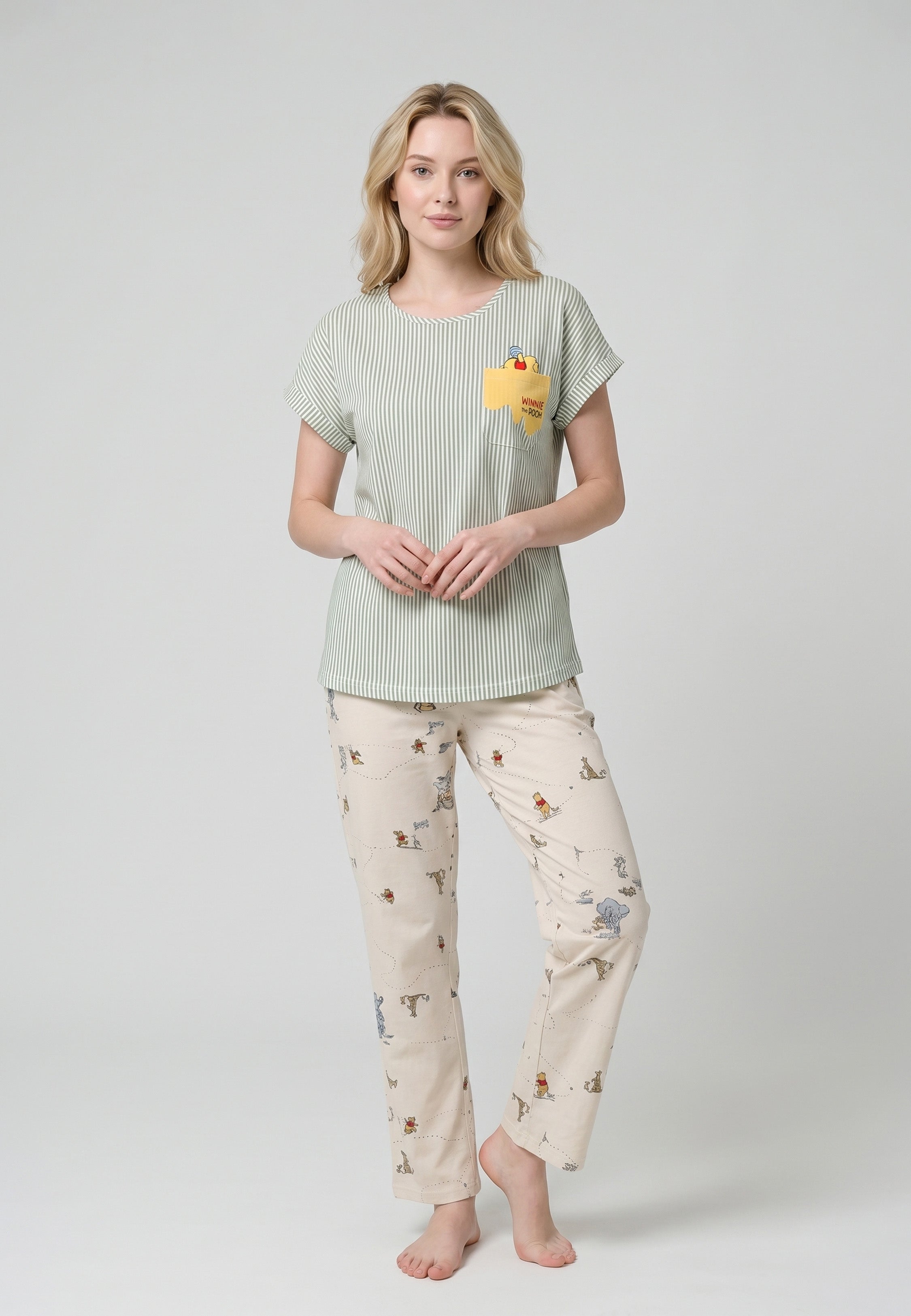 Femme portant un ensemble pyjama top col V seersucker rayé vert sauge poche patchée et pantalon imprimé all-over fond crème Rosabella