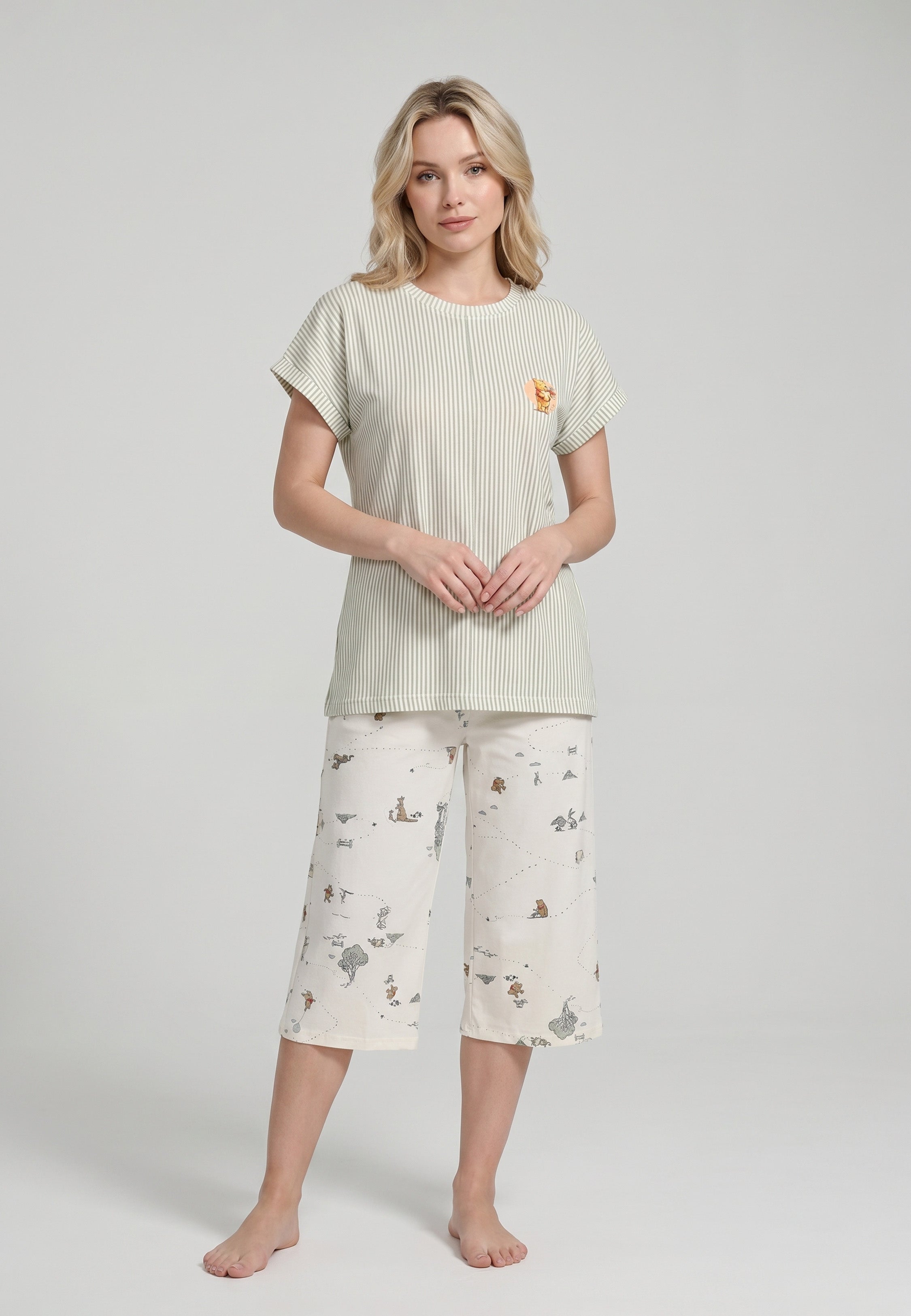 Femme portant un ensemble pyjama top col rond seersucker rayé vert sauge badge et pantacourt imprimé all-over fond crème Rosabella